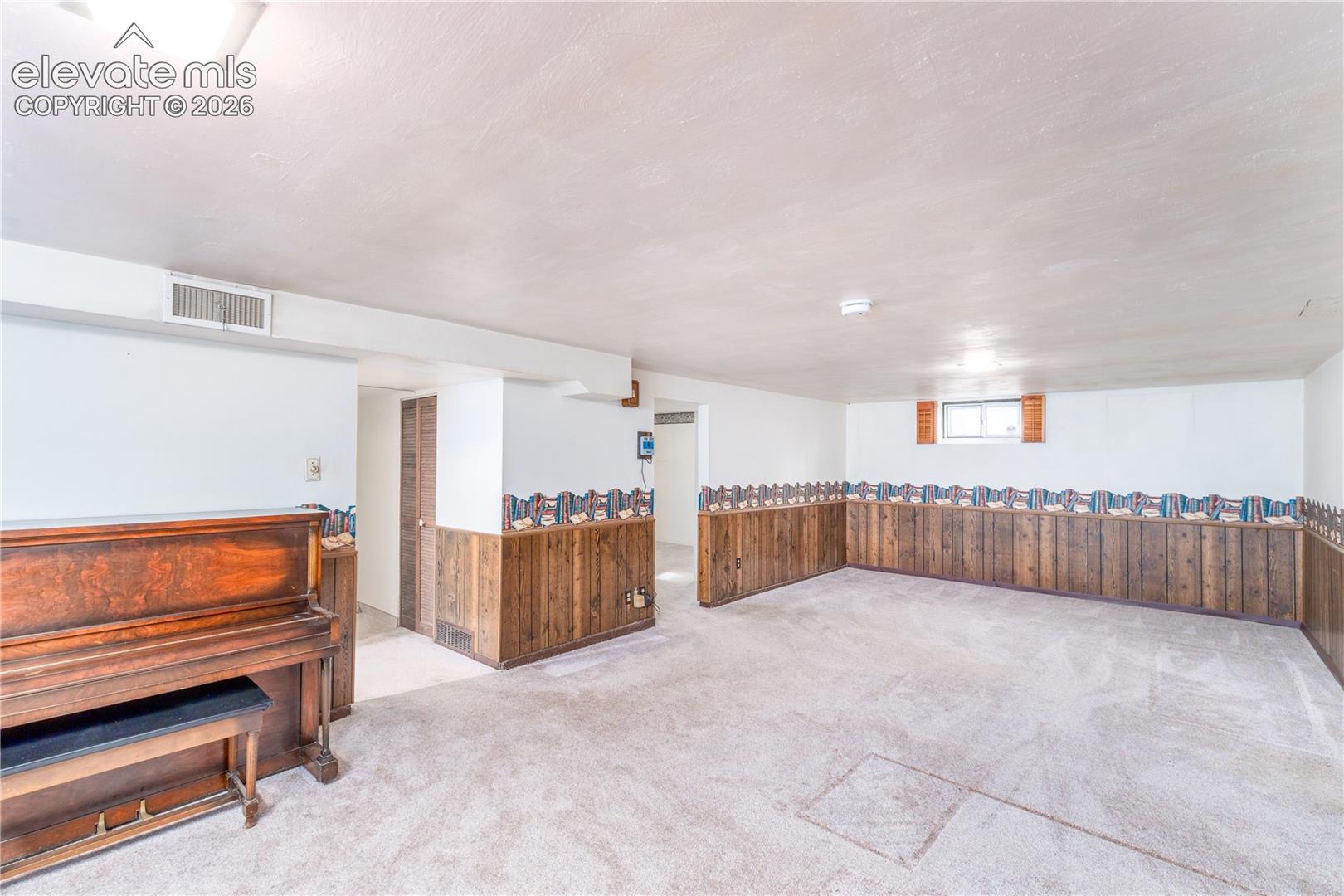 Spacious room featuring carpeted flooring and wood-paneled wainscoting