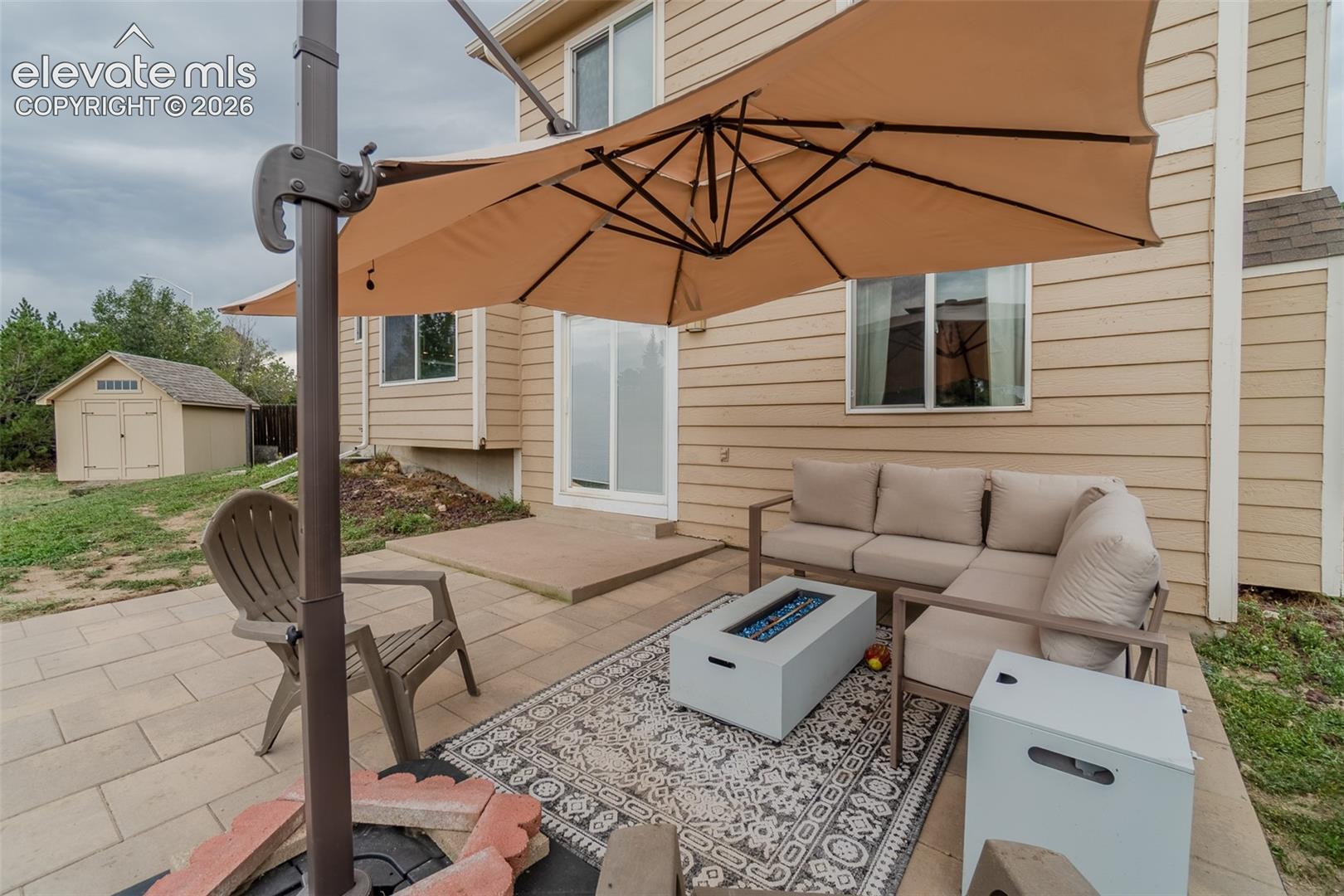 Paved patio with a built-in fire pit, offering direct access to the interior via a sliding glass door