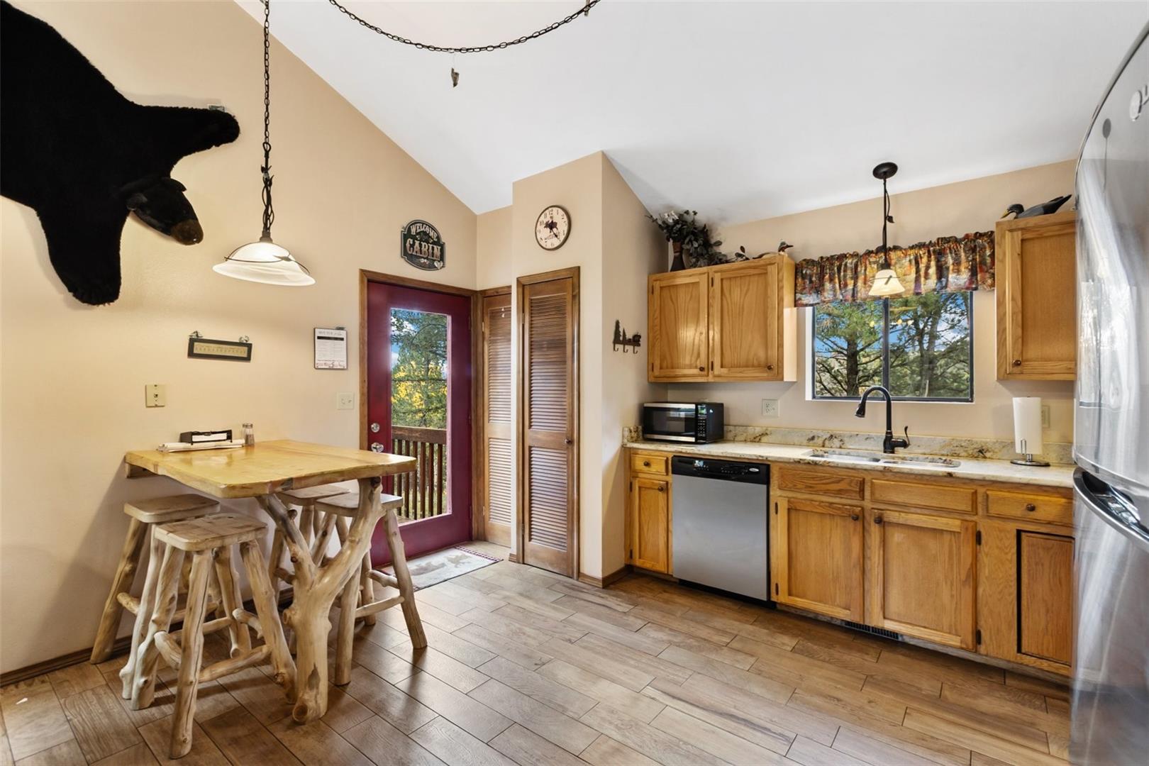 Vaulted ceiling, wood-finish flooring, natural wood cabinetry, stainless steel dishwasher, and built-in microwave