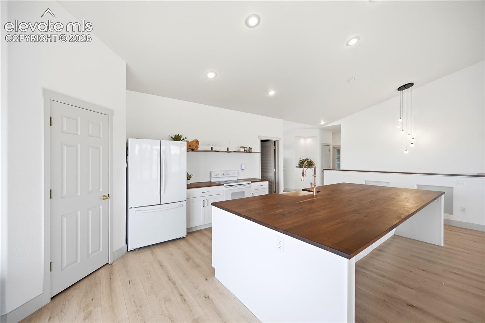 Kitchen featuring a large central island with a wood-finish surface, recessed lighting, wood-finish flooring, and open shelving