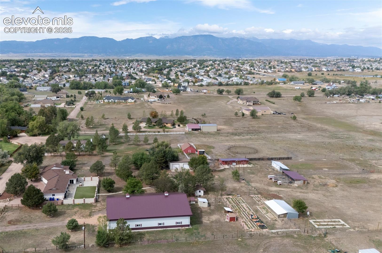 Expansive property featuring multiple outbuildings, fenced enclosures, and a prominent mountain backdrop