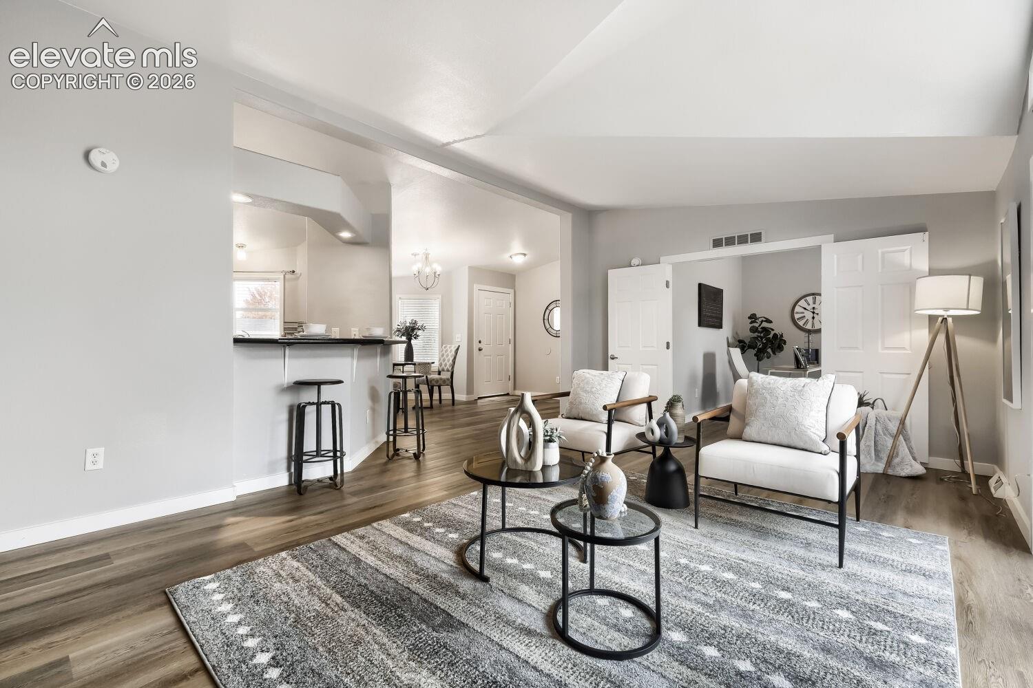 Open-concept interior featuring vaulted ceilings, wood-finish flooring, and a breakfast bar with built-in counter space