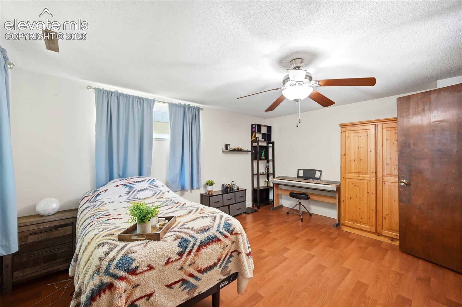 Wood-finish flooring, ceiling fan with integrated lighting, and built-in wood cabinetry
