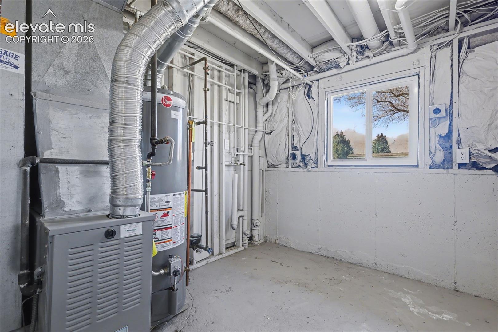 Mechanical room featuring a gas-fired furnace, water heater, concrete flooring, exposed ceiling joists, and a slider window
