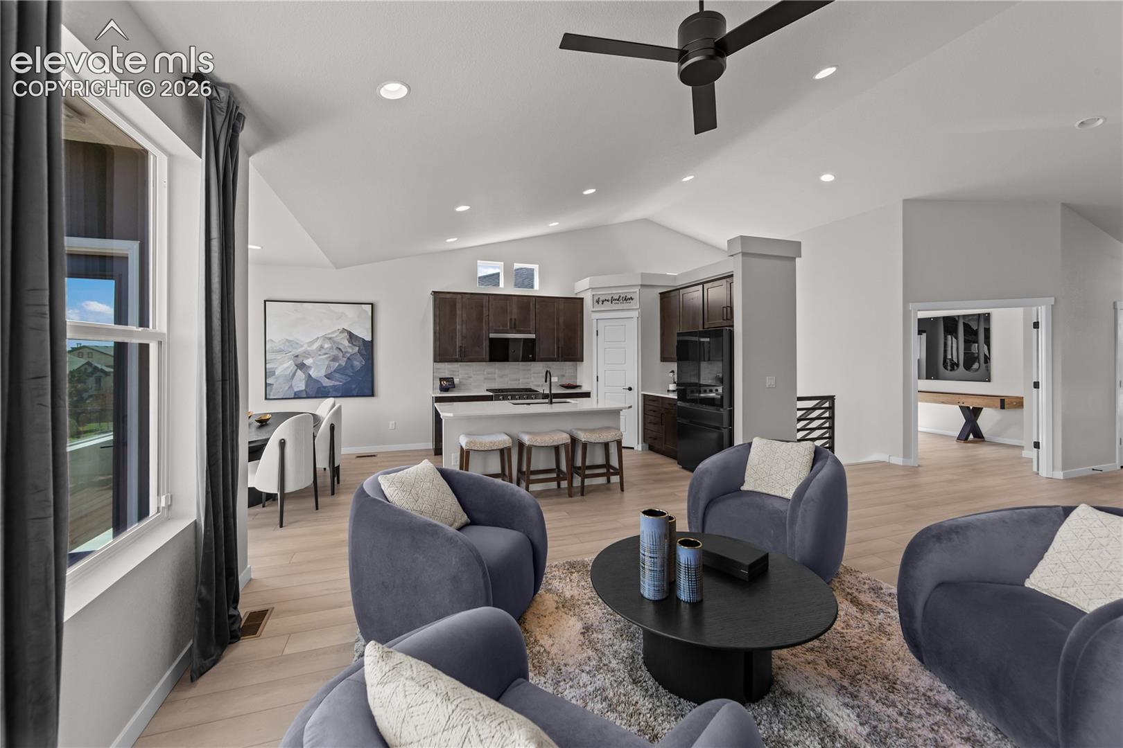 Vaulted ceilings, wood-finish flooring, kitchen island with built-in cabinetry, recessed lighting, and a ceiling fan