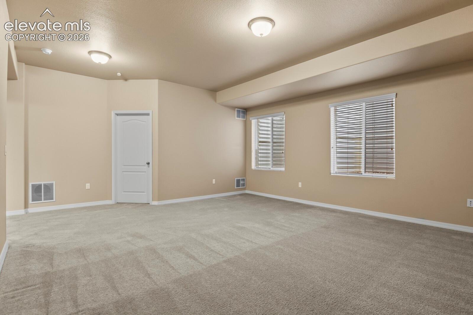 Spacious interior with neutral carpeting, recessed ceiling lighting, and multiple windows