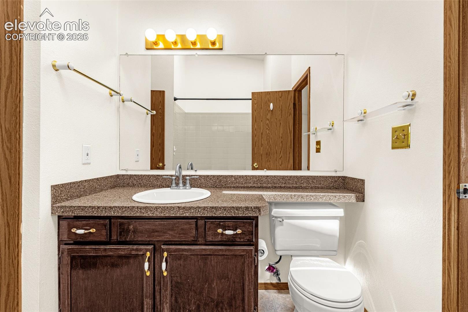 Bathroom vanity with a dark wood-finish cabinet and integrated sink, complemented by a speckled countertop