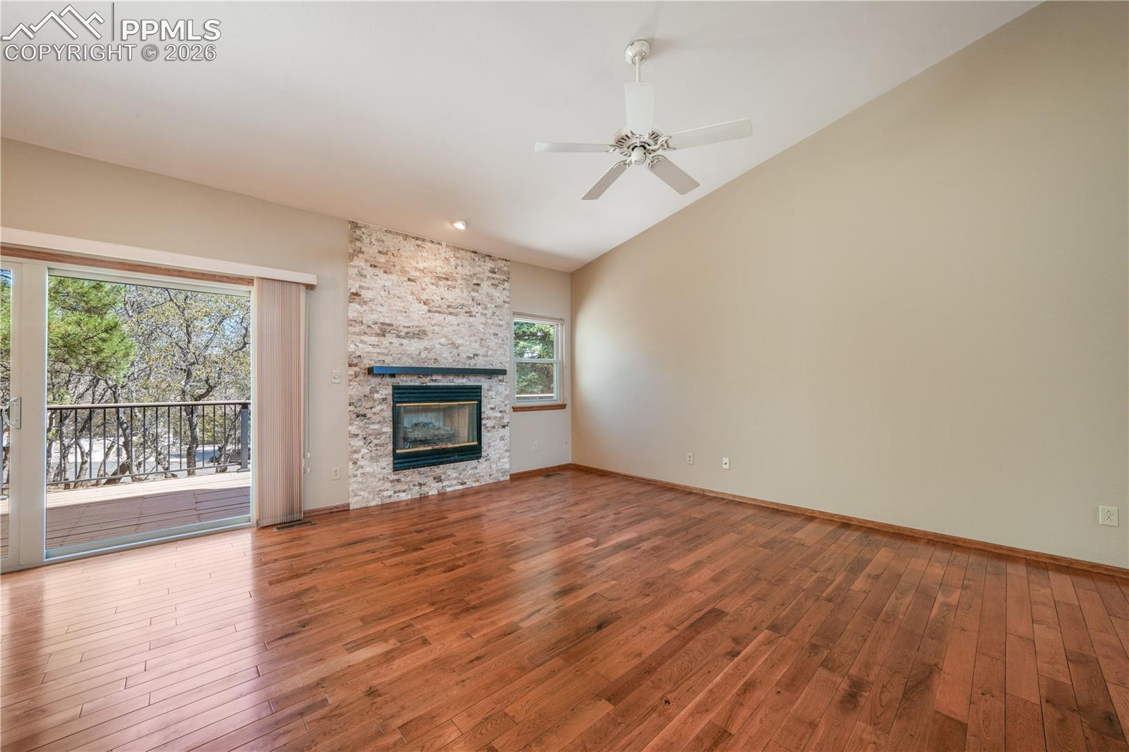 Main living room with hardwood floors, gas fireplace, extended patio doors to private deck