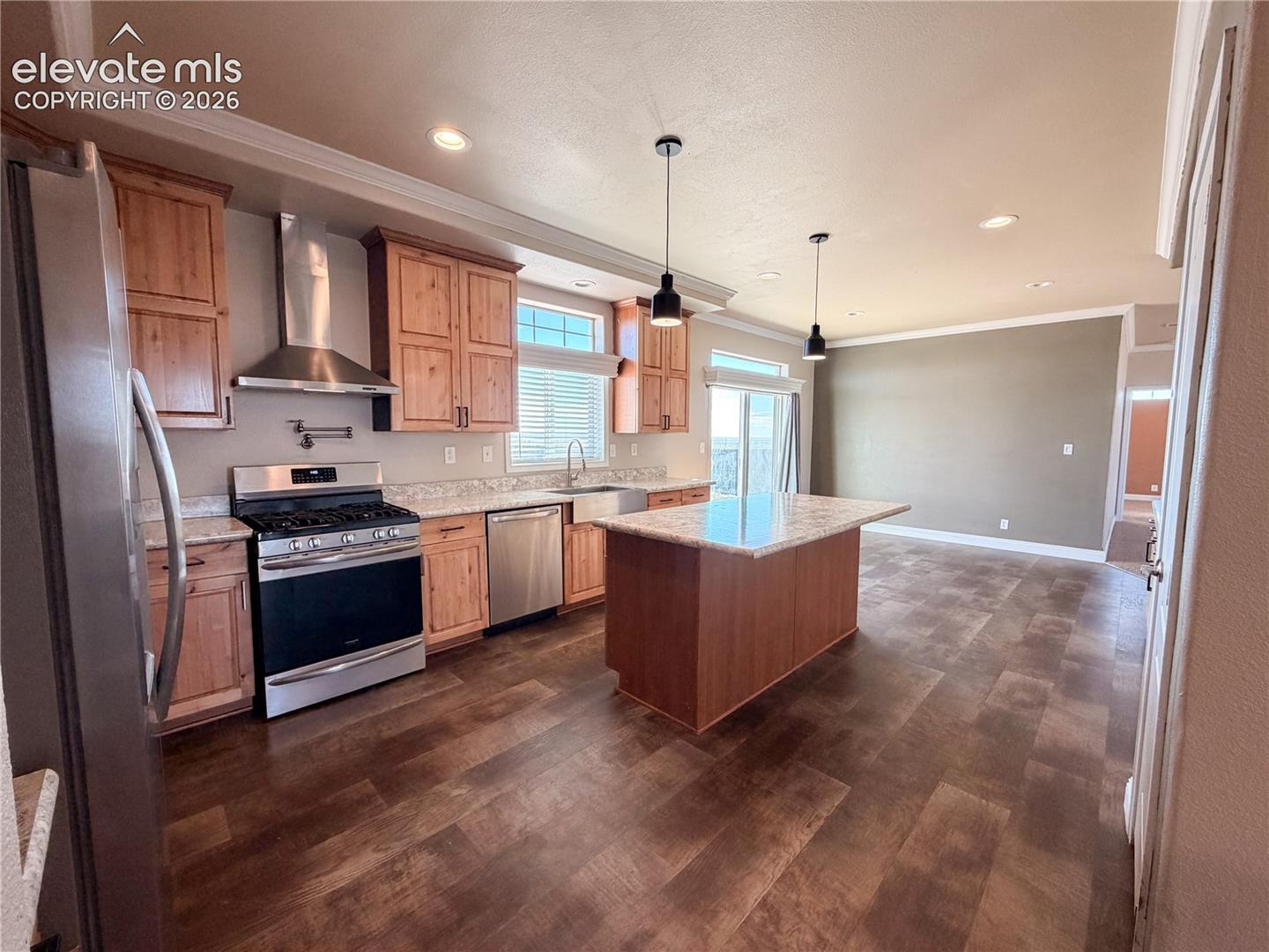 Kitchen featuring wood cabinetry, stainless steel appliances, a central island with countertop, and wood-finish flooring