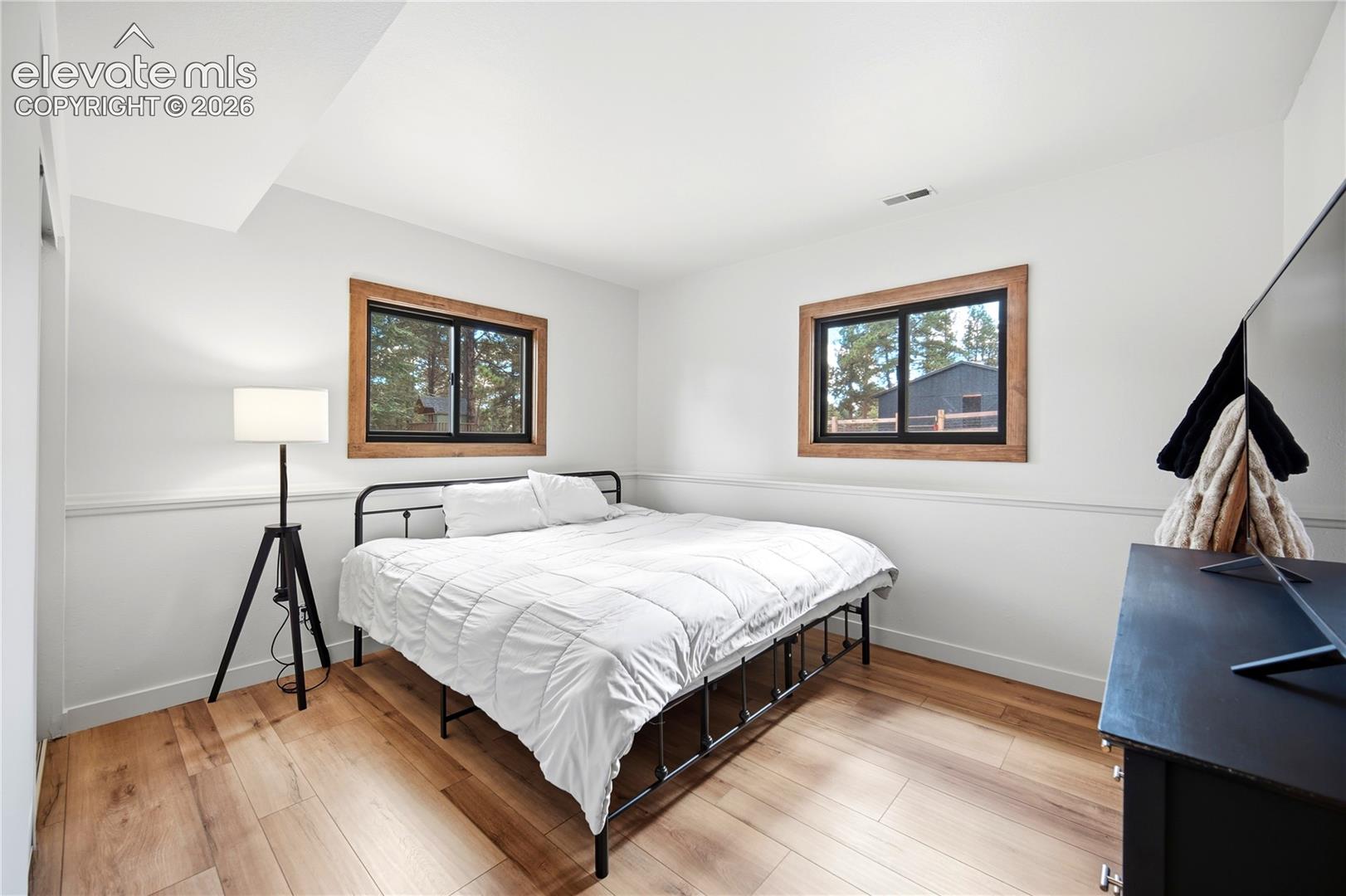 Interior room featuring wood-finish flooring, dual windows with natural wood trim, and chair rail molding
