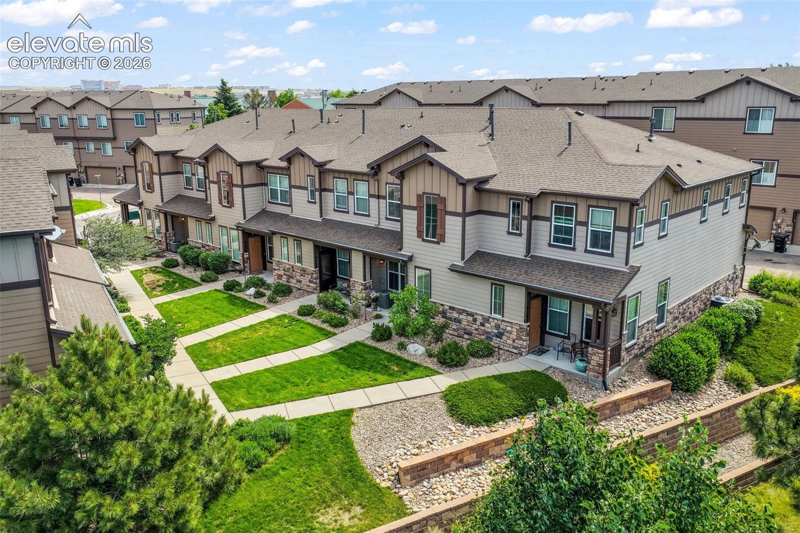 Multi-level townhome exterior featuring stone accents and vertical siding, paired with a gabled roofline