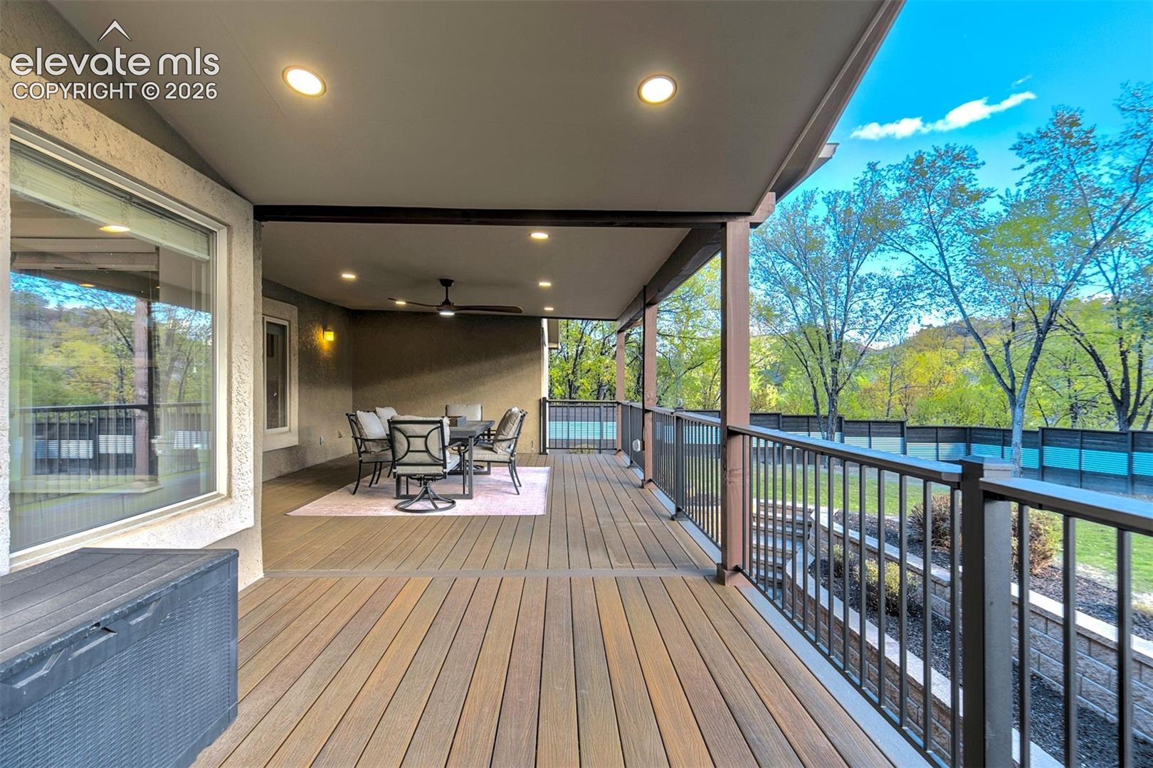 Covered outdoor deck featuring composite decking, recessed lighting, a ceiling fan, and metal balustrade railing