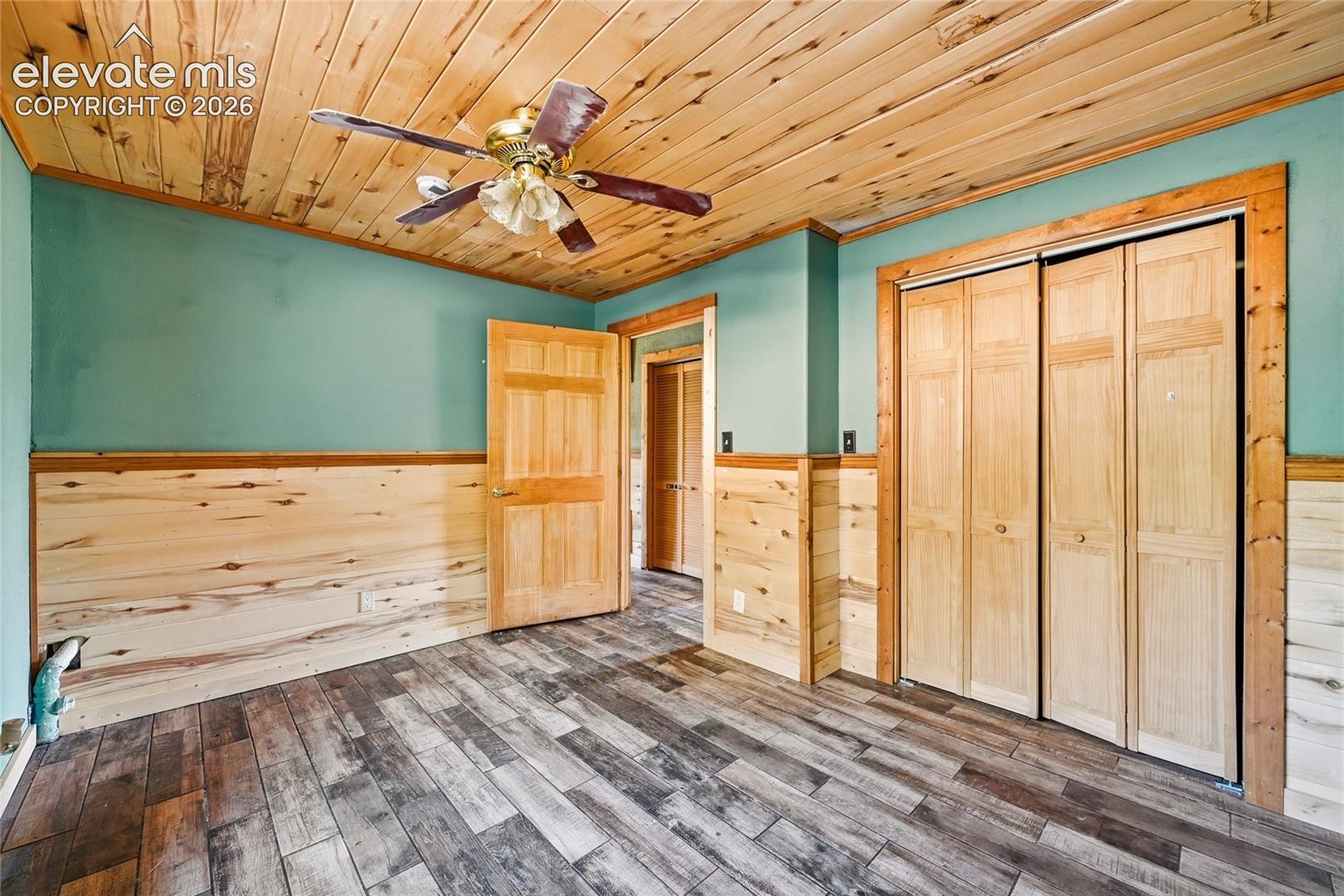 Wood-finish flooring, wood-paneled ceiling, wood wainscoting, wood bi-fold closet doors, and wood interior door