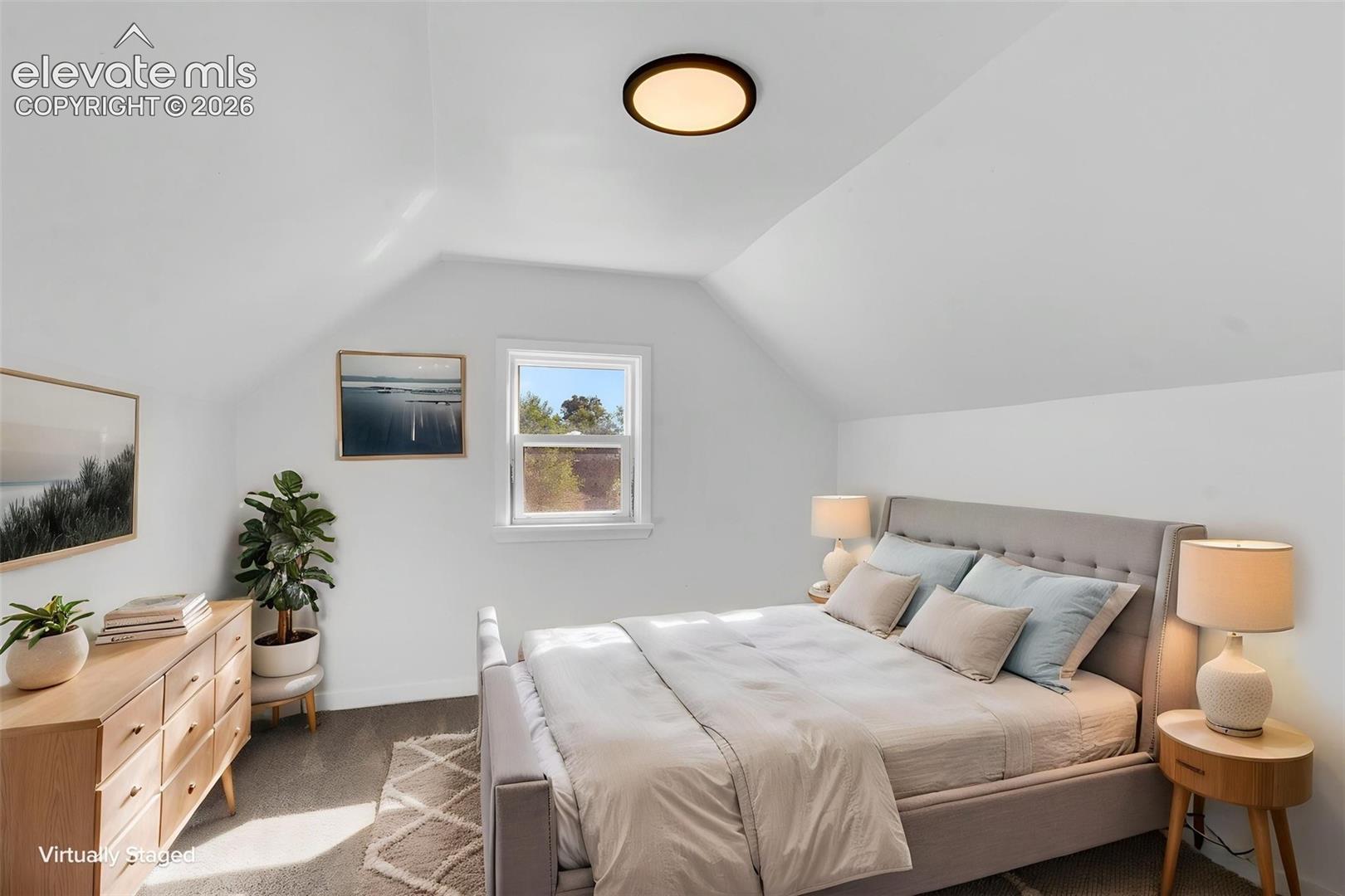 Vaulted ceiling, neutral carpet flooring, single-pane window, and flush-mount circular lighting fixture