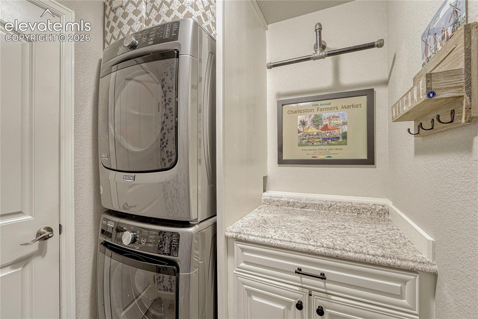 The dedicated laundry room adds everyday convenience with a stacked Maytag washer and dryer, custom cabinetry, and a practical folding area.