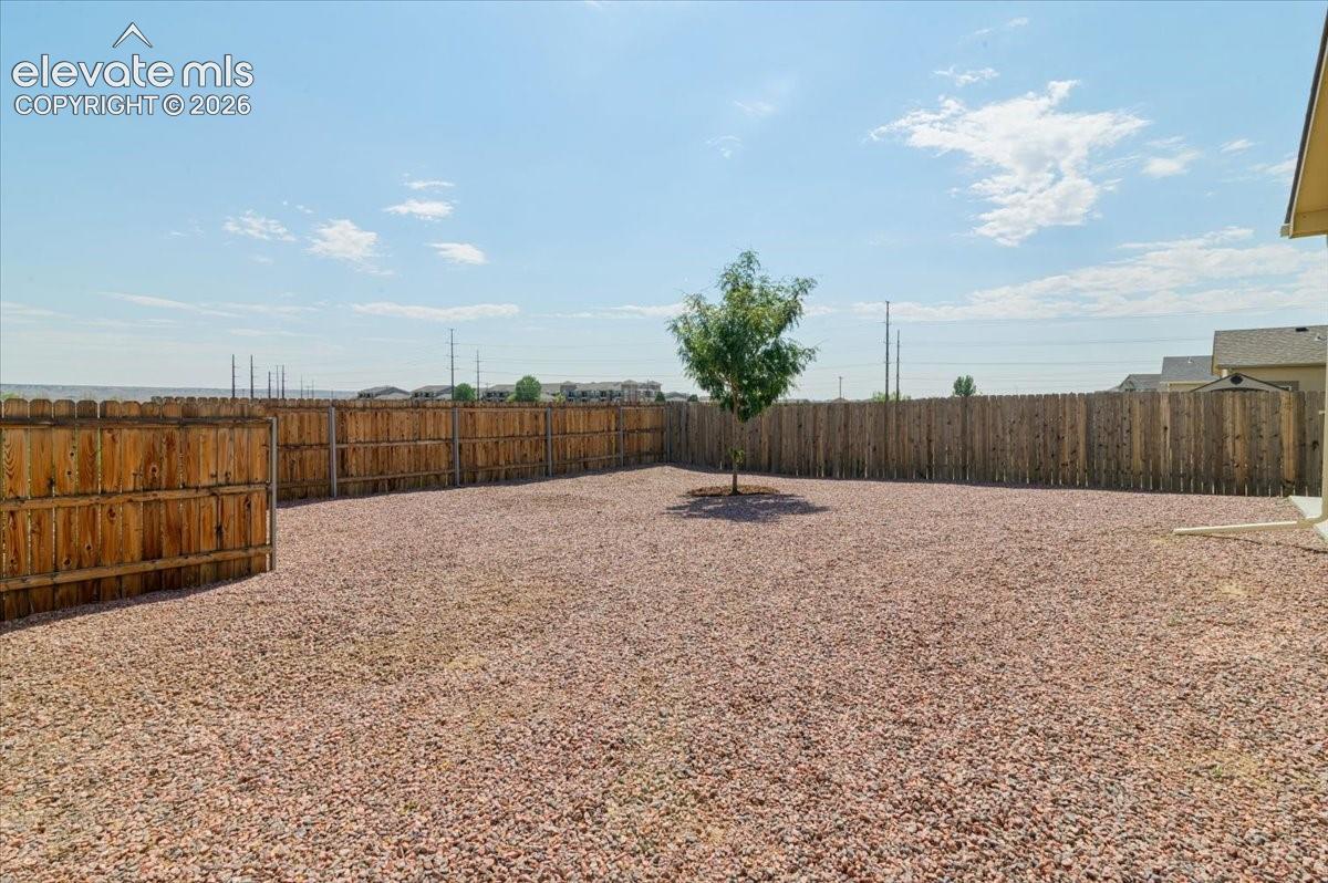 Expansive backyard featuring a full privacy fence and gravel landscaping