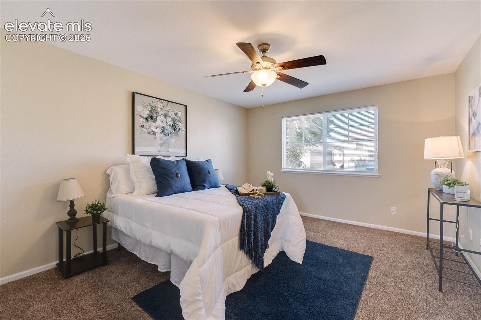 Neutral-toned interior space featuring carpeting, a ceiling fan with integrated light fixture, and a single-pane window