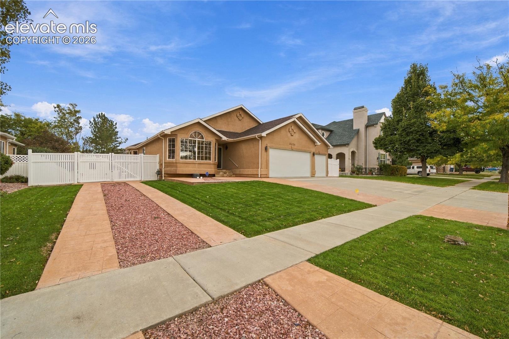 Stucco exterior residence featuring an arched window, a three-car garage, and white vinyl perimeter fencing
