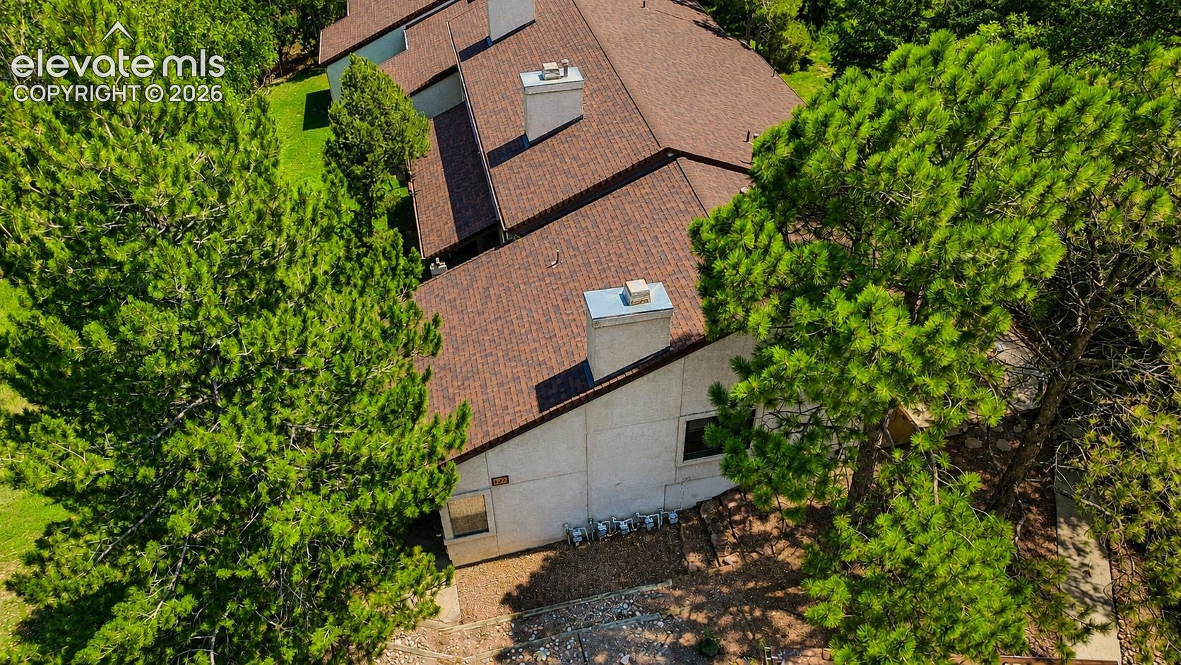 Aerial view of complex and treed lot.