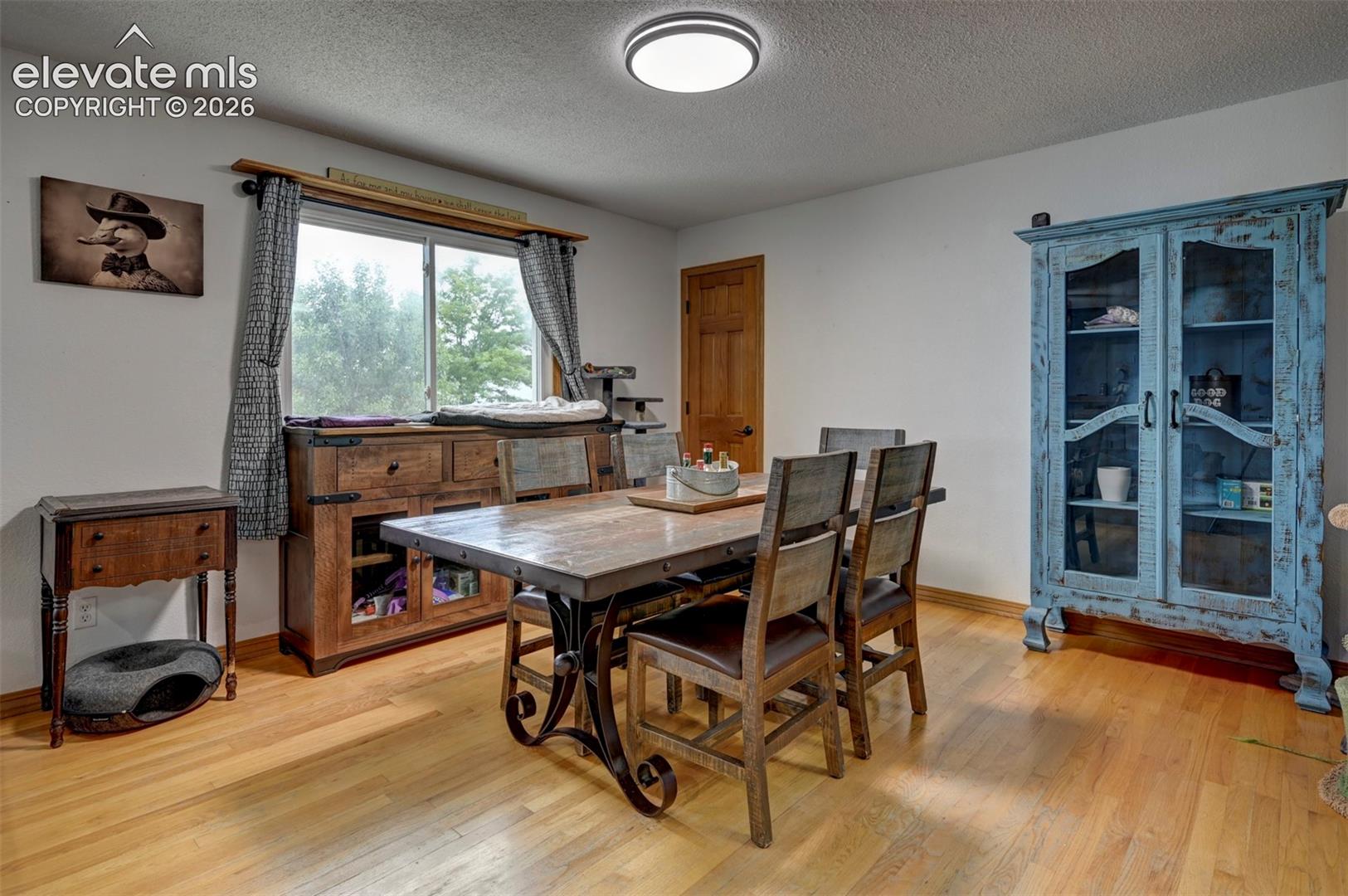 Hardwood flooring, white walls, flush mount ceiling light, and a natural wood interior door