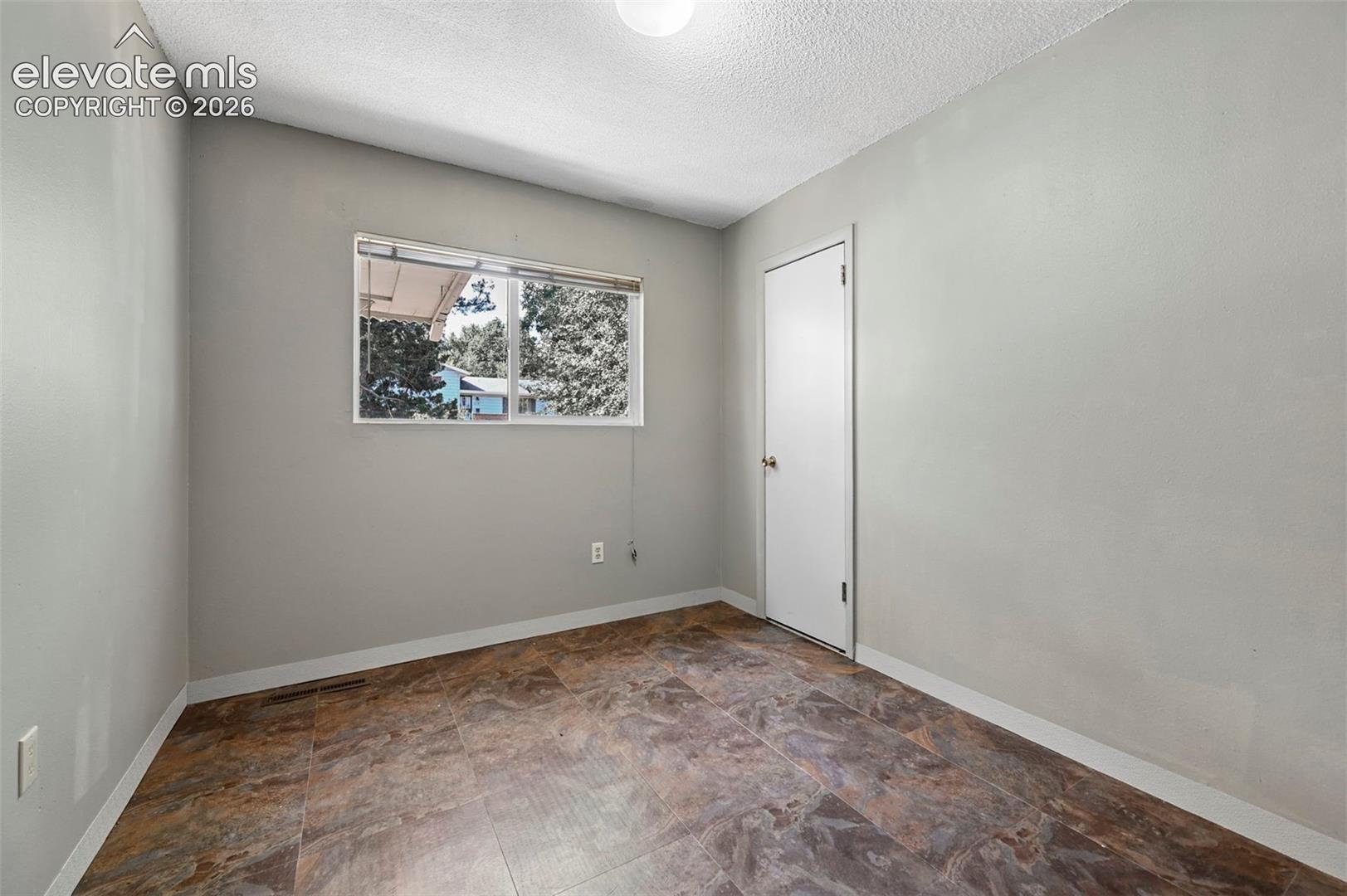 Room featuring a light gray wall color, a single window, and multi-toned flooring