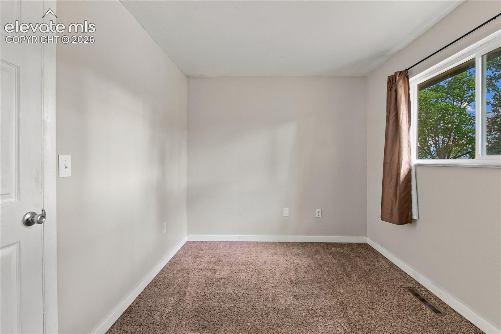 Main level bedroom with large window, carpet and closet space