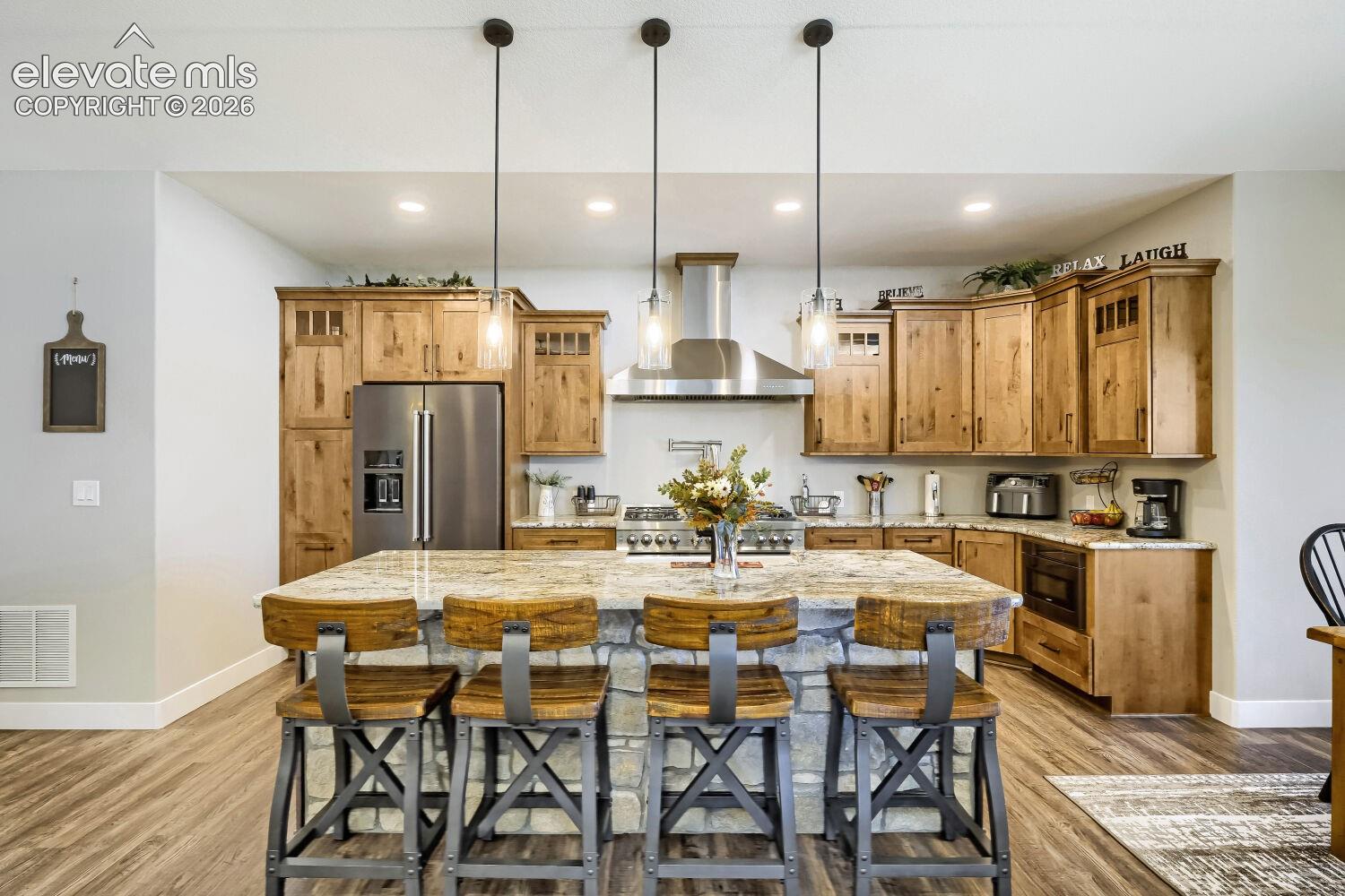 Kitchen featuring wood-finish flooring and a stone-faced island with a substantial countertop