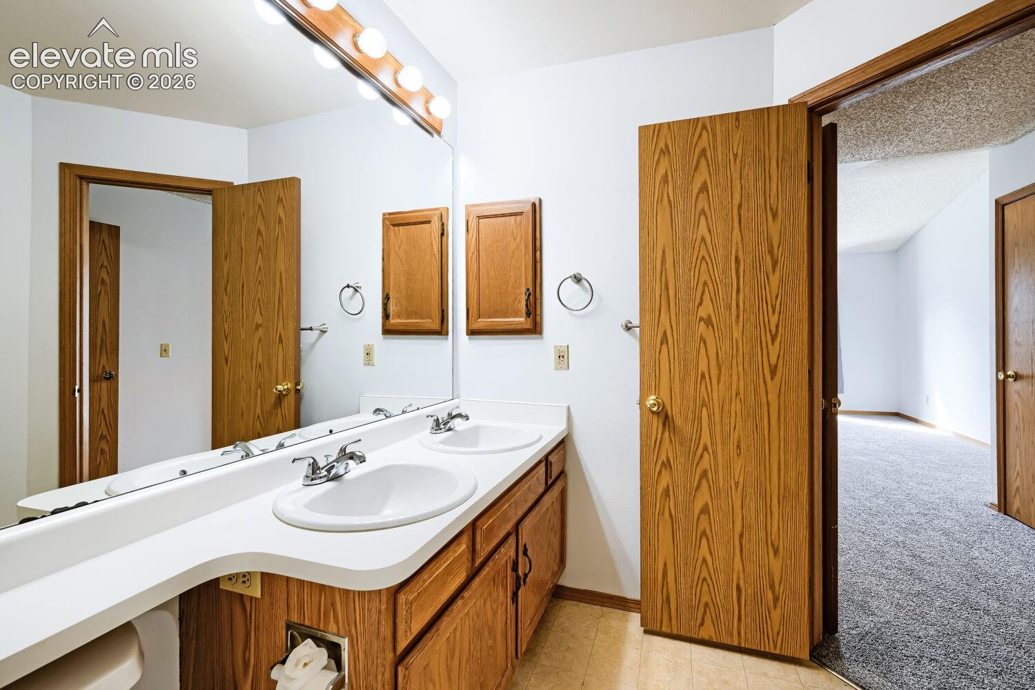 Dual-sink vanity with wood-finish cabinetry, white countertop, and chrome fixtures