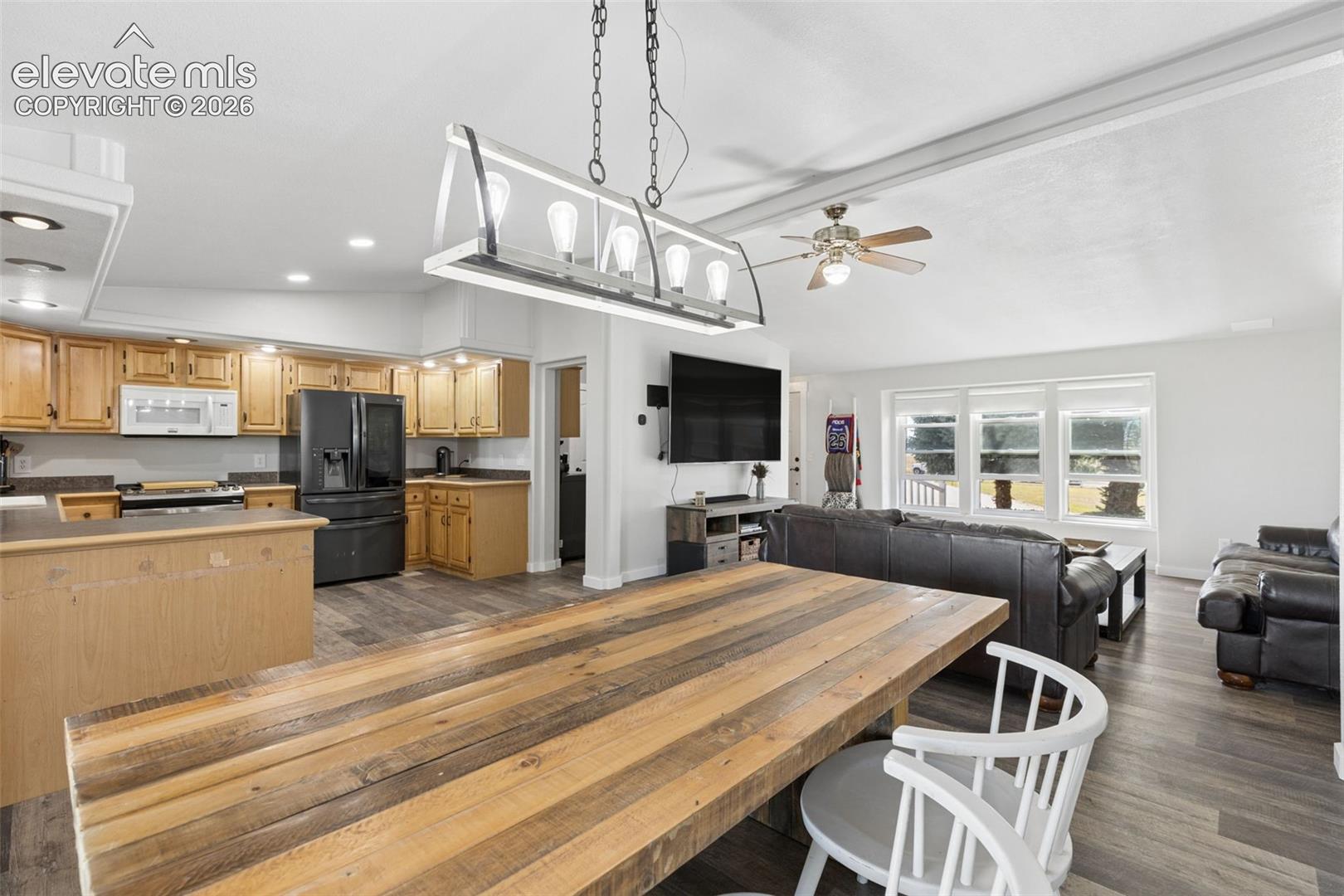 Kitchen featuring wood cabinetry, recessed lighting, and a linear multi-bulb pendant fixture, complemented by wood-finish flooring and expansive windows