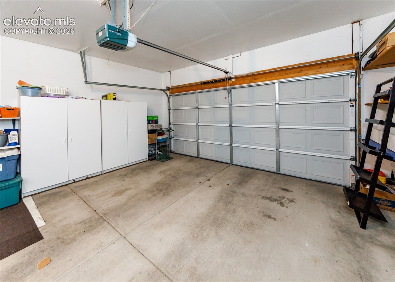 Multi-car garage featuring a sectional overhead door, concrete flooring, and built-in white cabinetry