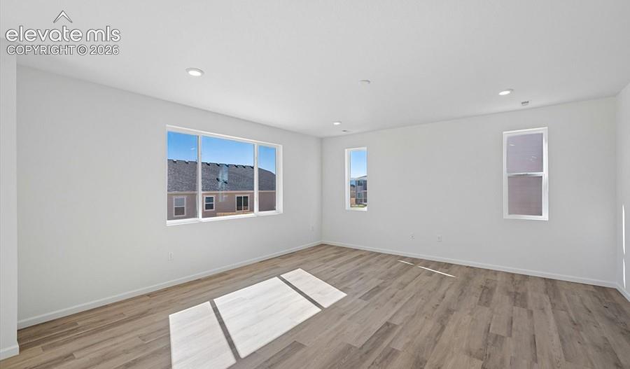 Neutral-toned walls, wood-finish flooring, recessed lighting, and multiple windows