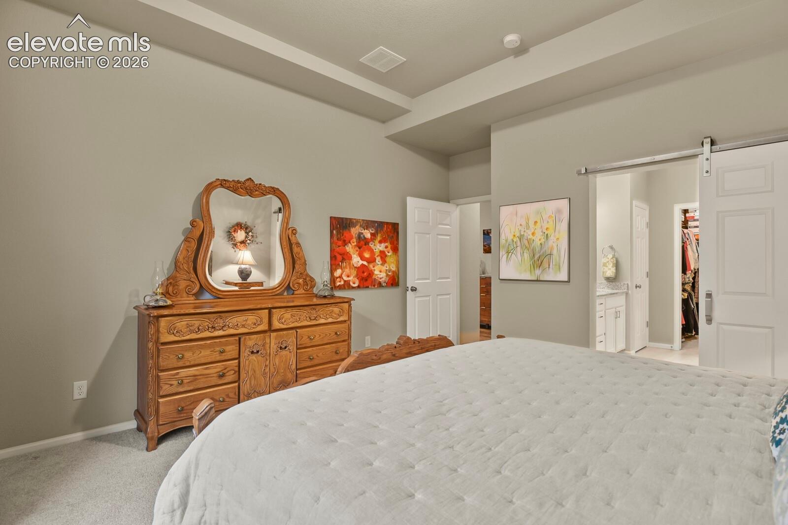 Tray ceiling featuring recessed lighting and a sliding barn-style door