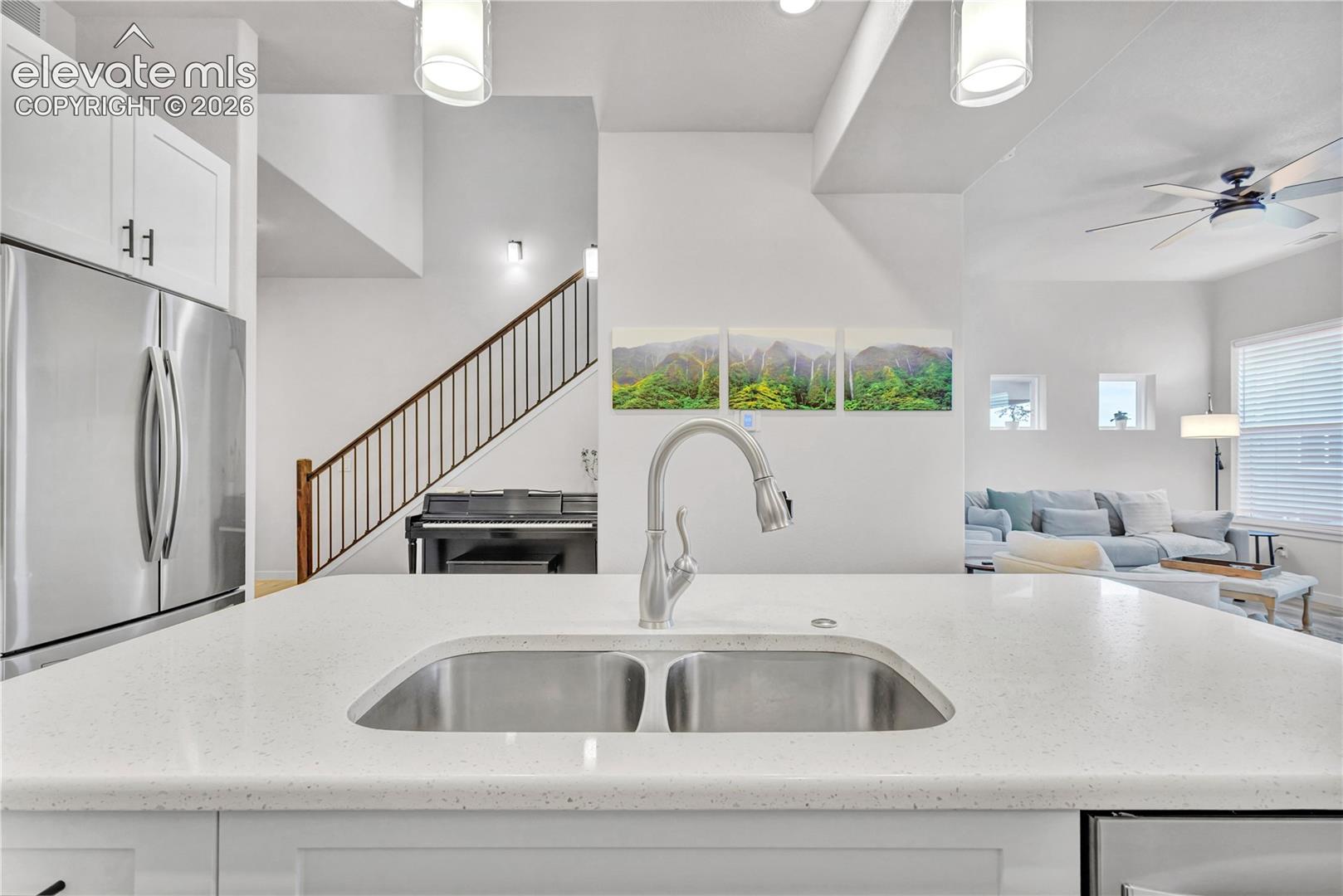 Spacious kitchen island with an undermount stainless steel double sink, a gooseneck faucet, and light-toned countertops
