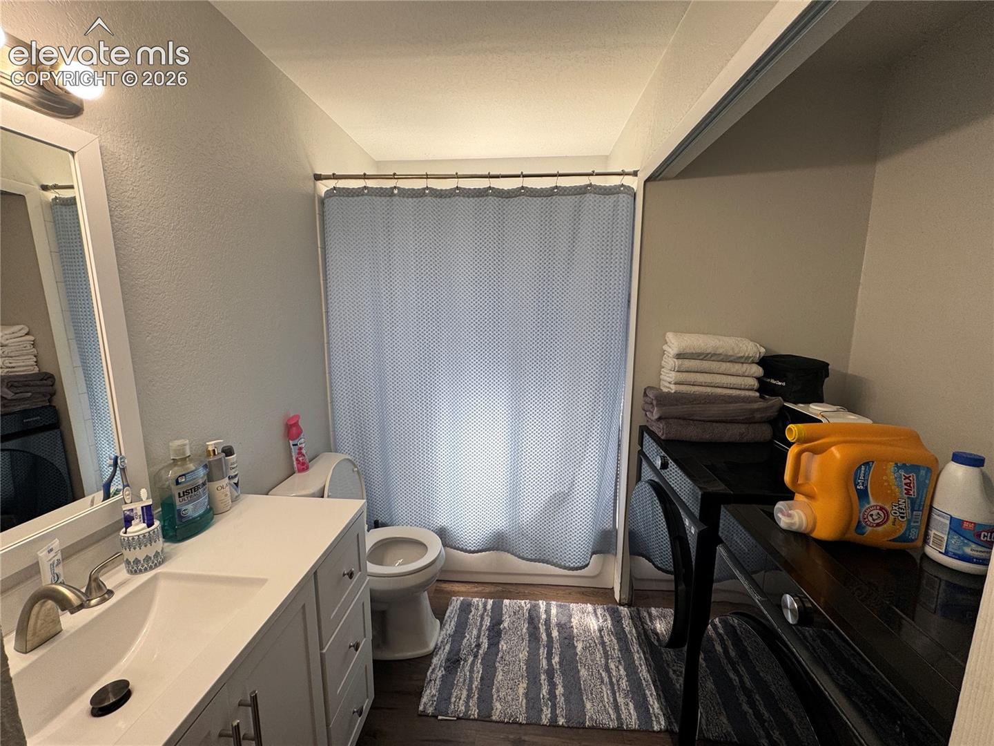 Bathroom featuring a single-sink vanity with white countertop, chrome faucet, wall-mounted mirror, and a shower/tub combination