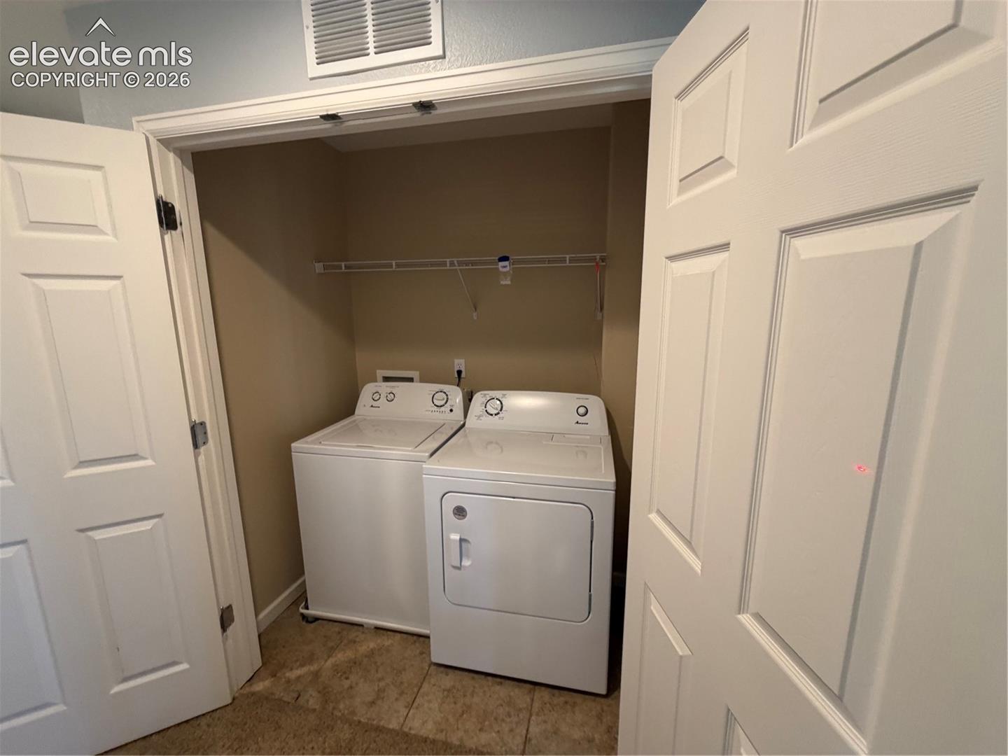 Dedicated laundry closet with white appliances and wire shelving