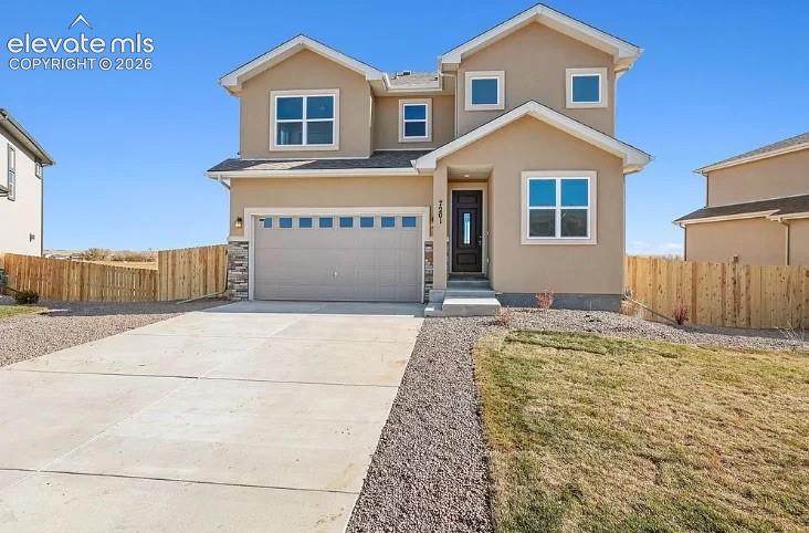 Two-story exterior featuring a stucco facade, multi-gabled roofline, stone veneer accents, an attached two-car garage, and wood-style privacy fencing