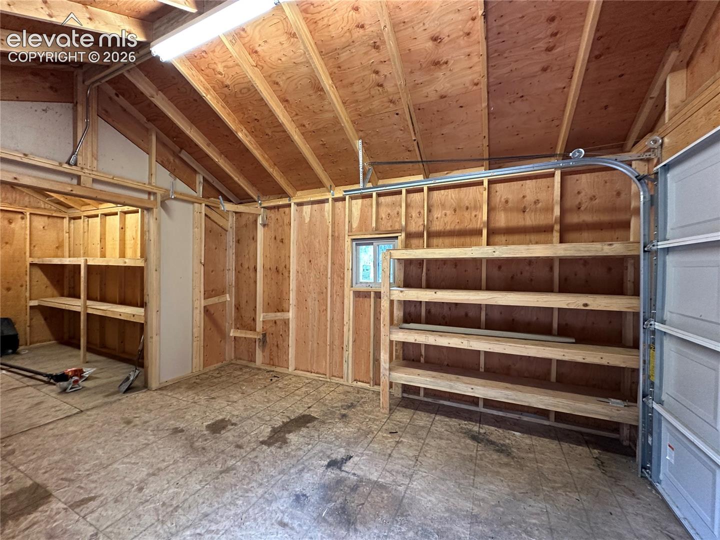 Storage shed with overhead door and shelves.