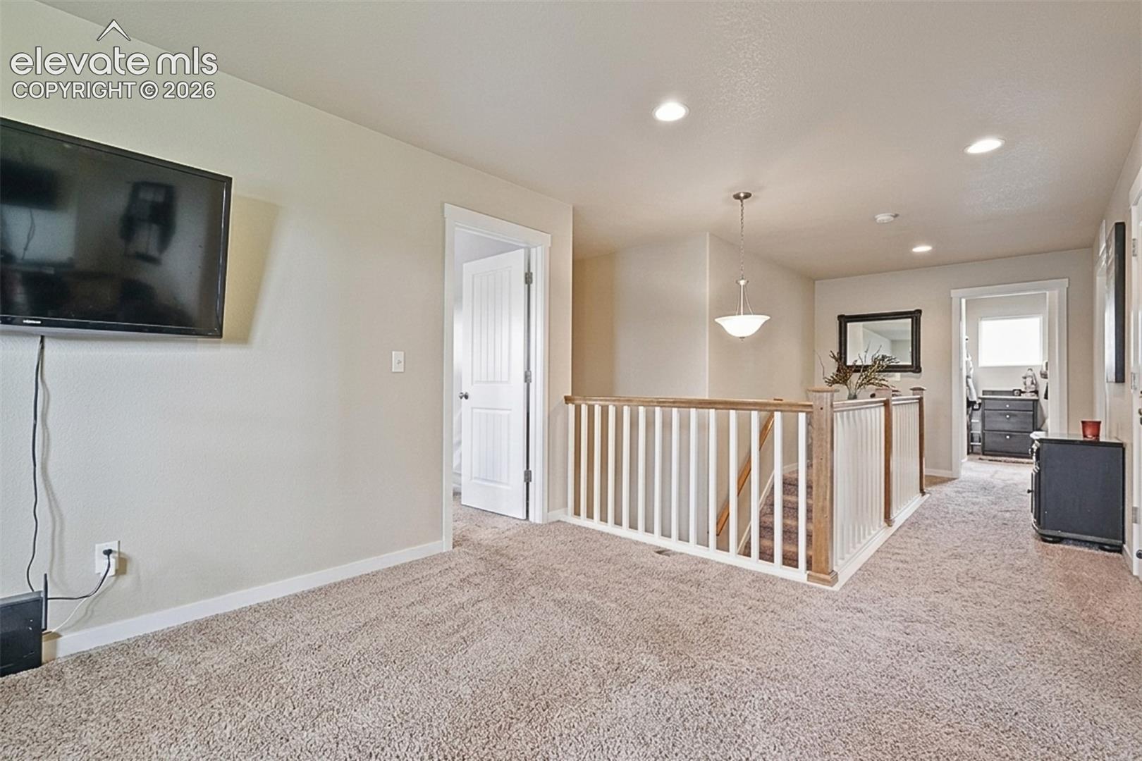 Upper Level: Carpeted landing with white balusters and a wood-finish handrail