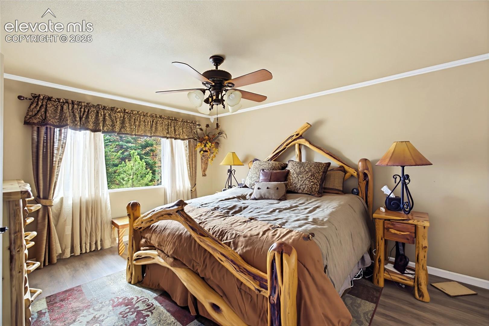 Interior room featuring wood-finish flooring, a multi-light ceiling fan, and a large window with exterior greenery