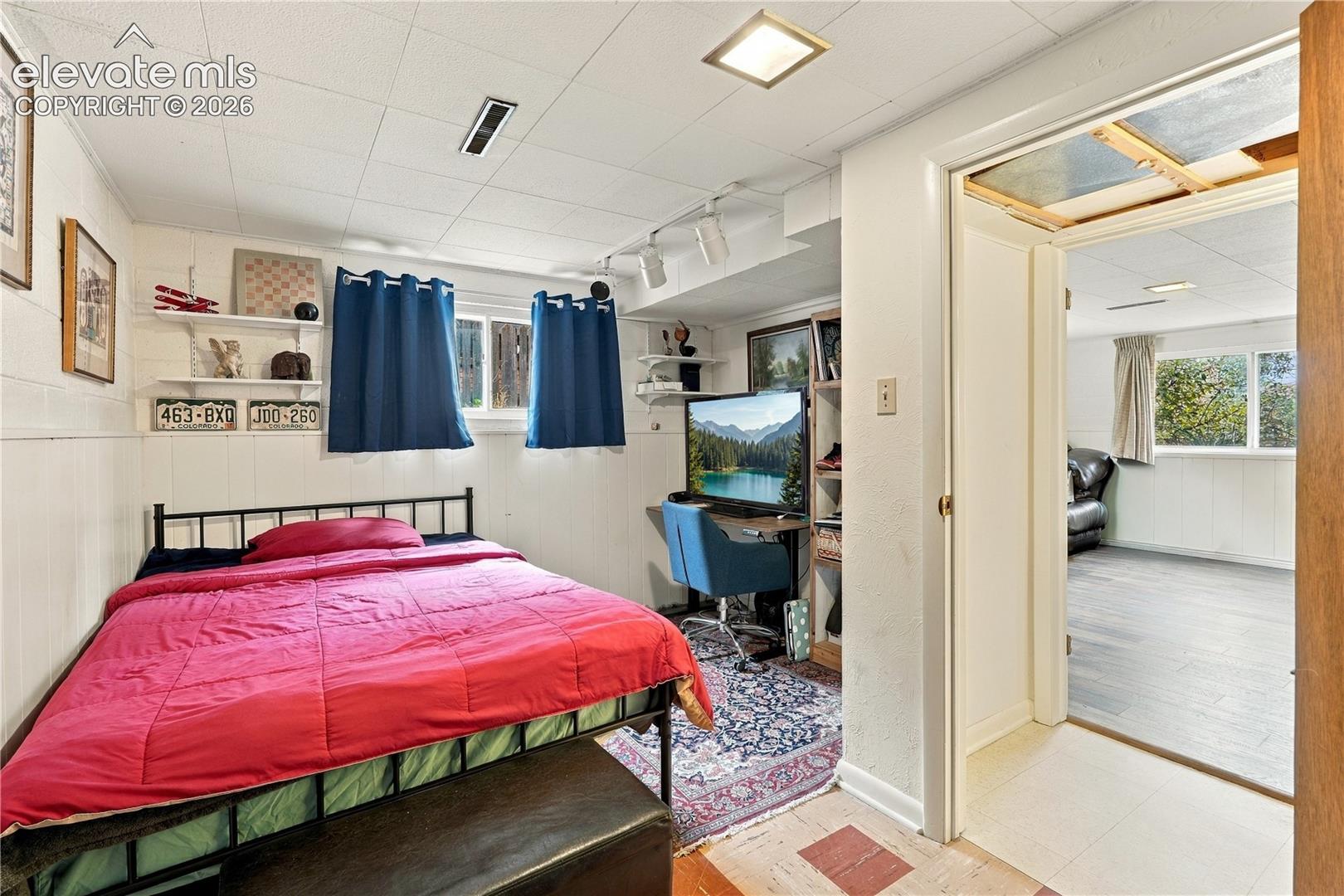 Interior space featuring painted masonry walls, built-in shelving units, recessed square lighting, track lighting, and a multi-panel door entry