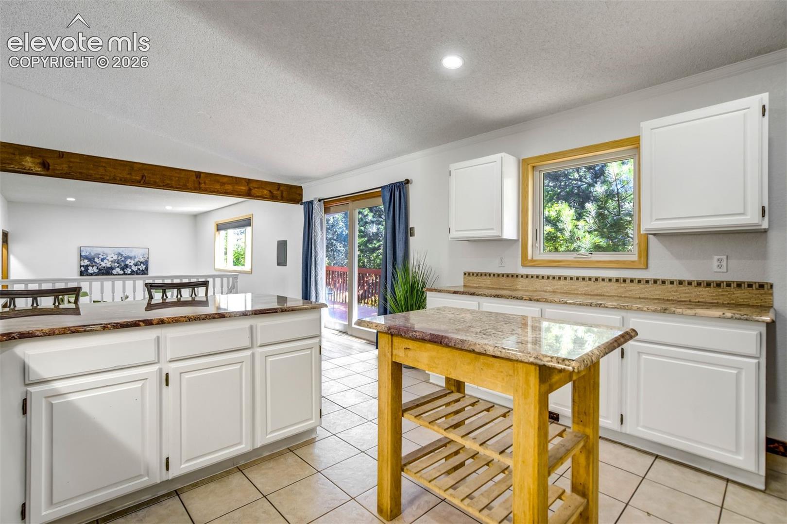 Kitchen featuring white cabinetry, light-toned countertops, and tile flooring