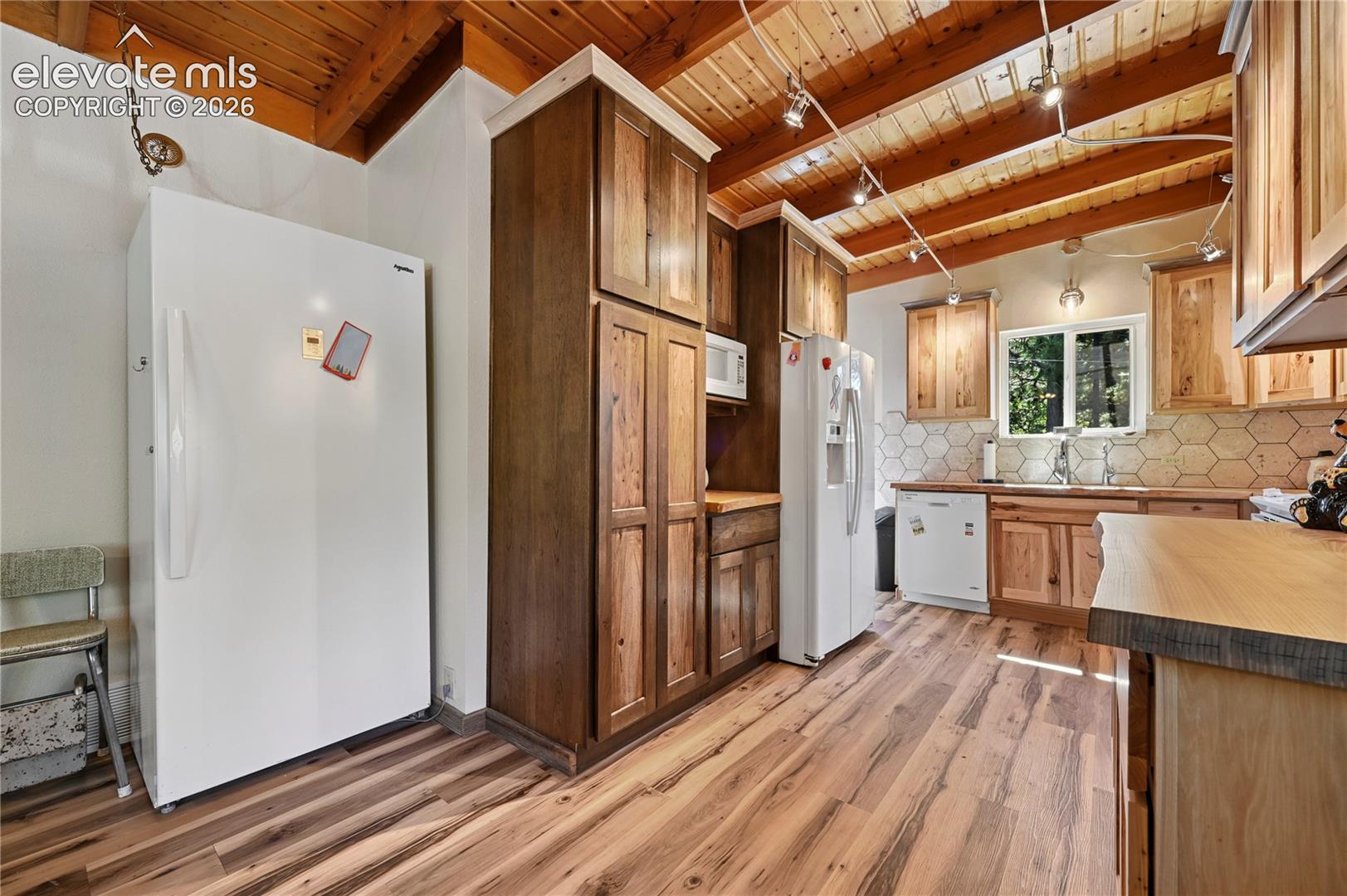 Wood-finish flooring throughout, complemented by wood cabinetry and a wood-slat vaulted ceiling