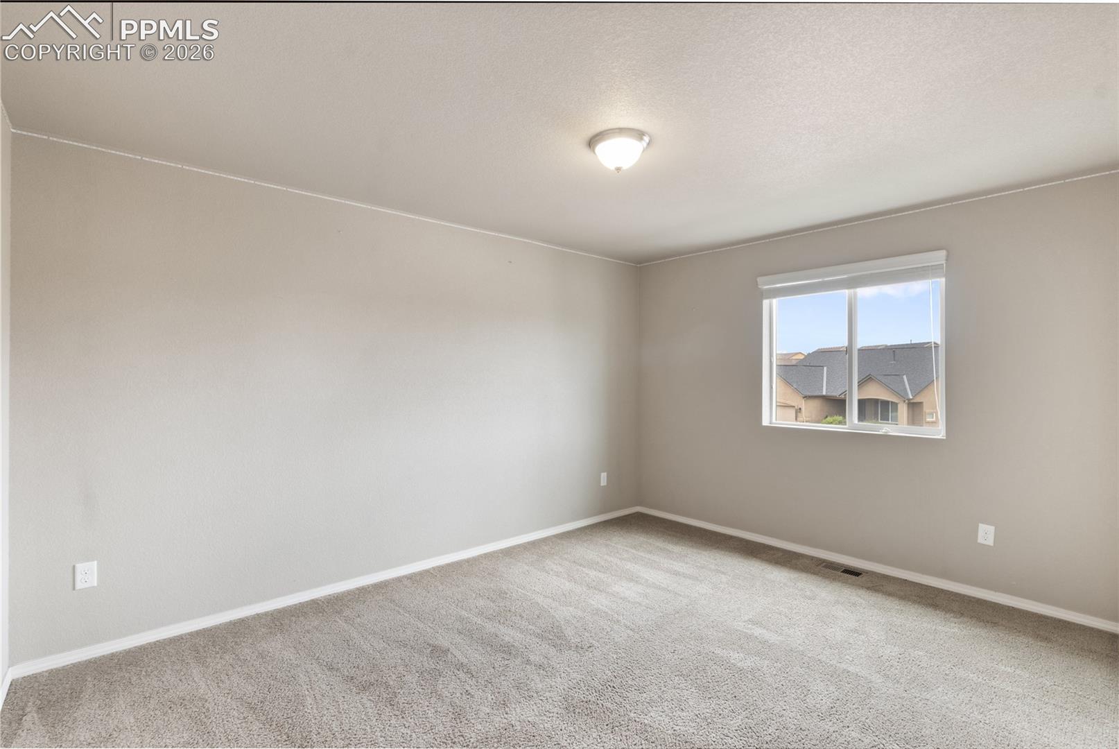 Featuring light colored carpet and a textured ceiling
