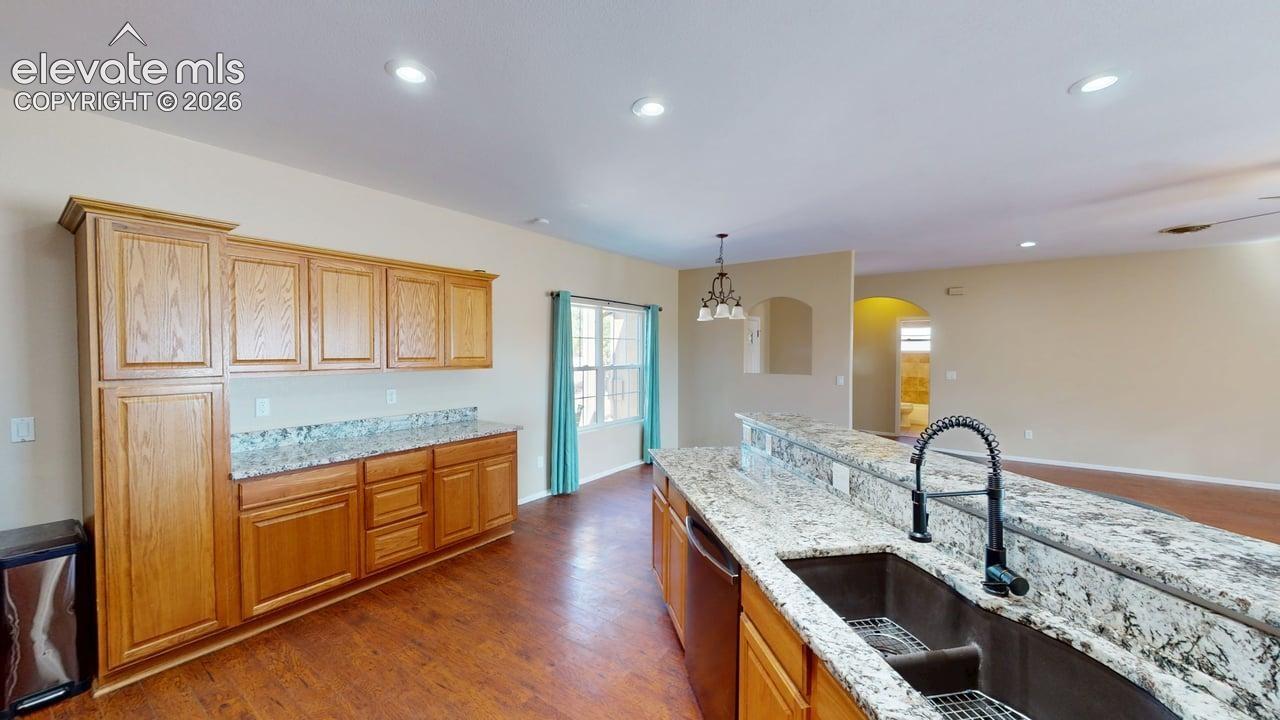 Expansive island with a double basin sink and a contemporary faucet, complemented by wood-finish cabinetry and light-toned countertops