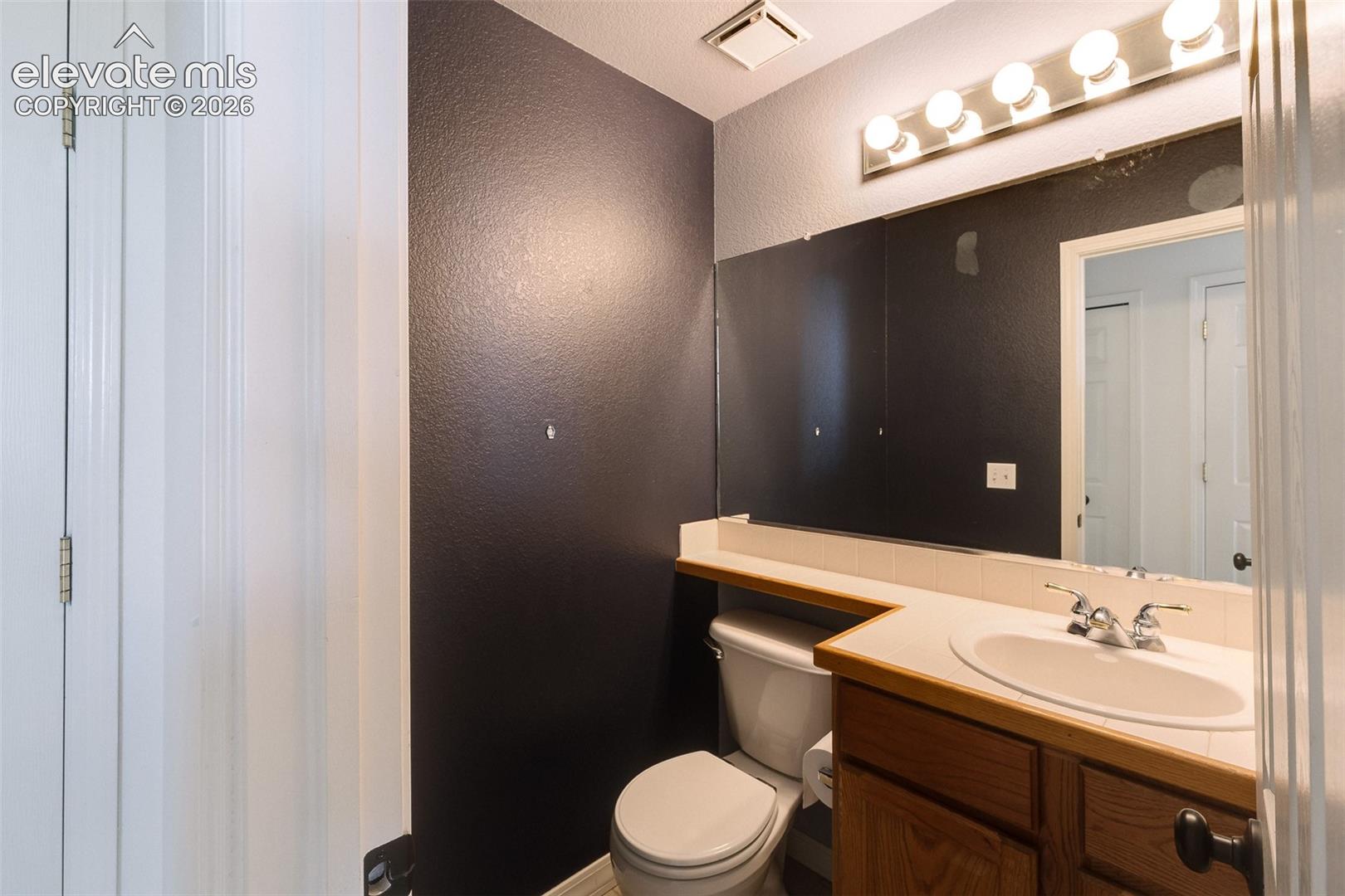 Bathroom vanity with a built-in sink, wood-finish cabinetry, and a full-width mirror