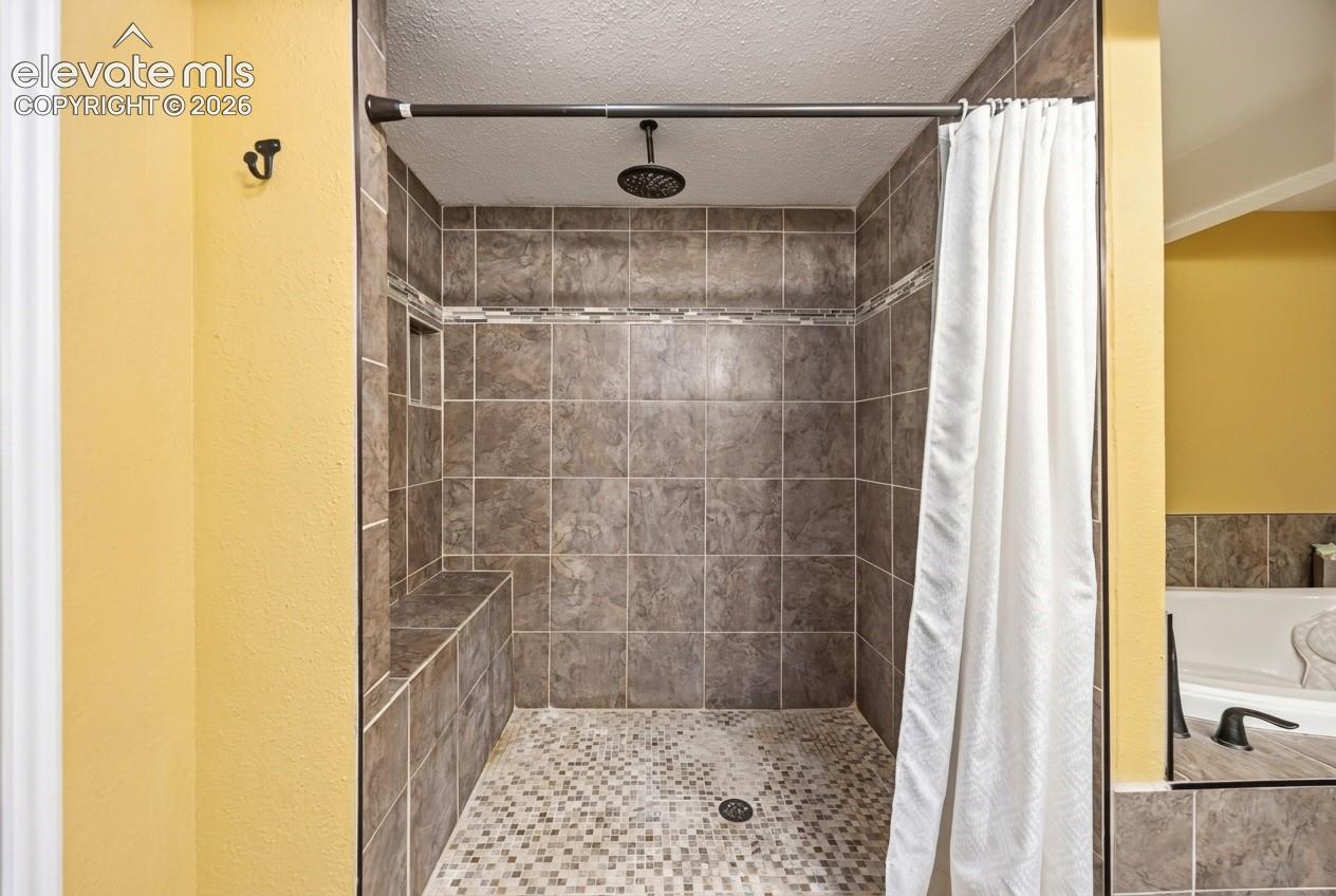 Tiled shower enclosure featuring a built-in bench, recessed shelf, and mosaic tile flooring