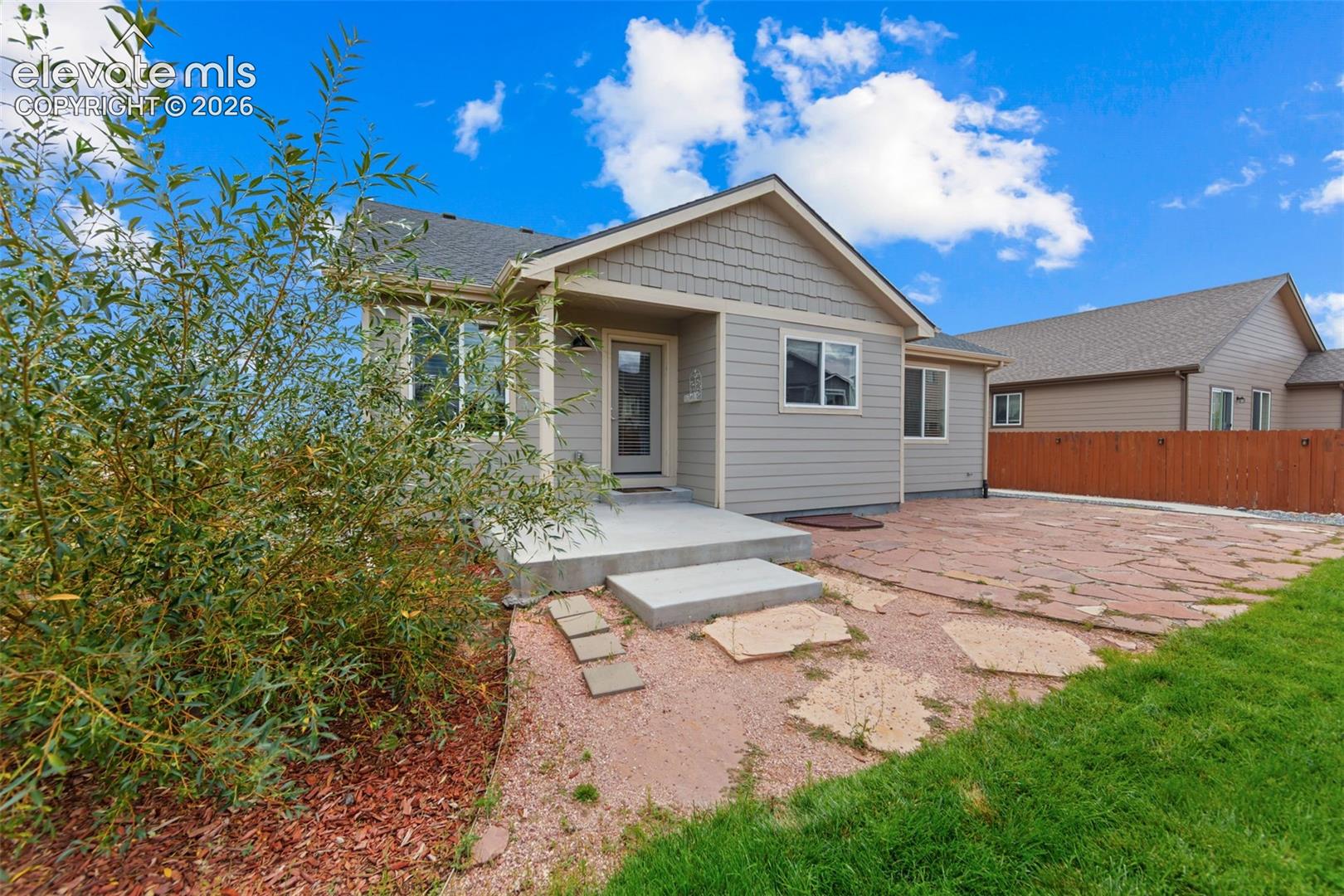 Siding exterior with decorative shake accents, an inviting concrete front porch, and a flagstone patio area