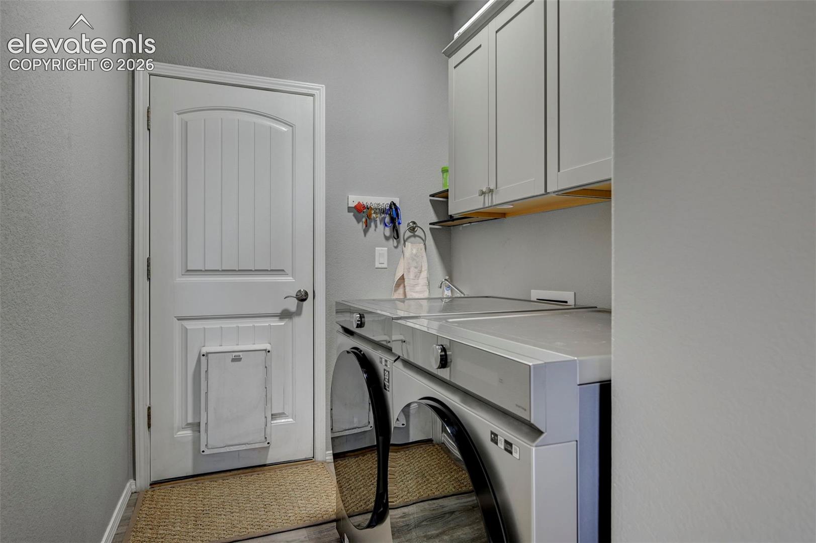 Laundry area with shaker-style upper cabinetry, an integrated countertop, and a wood-finish shelf