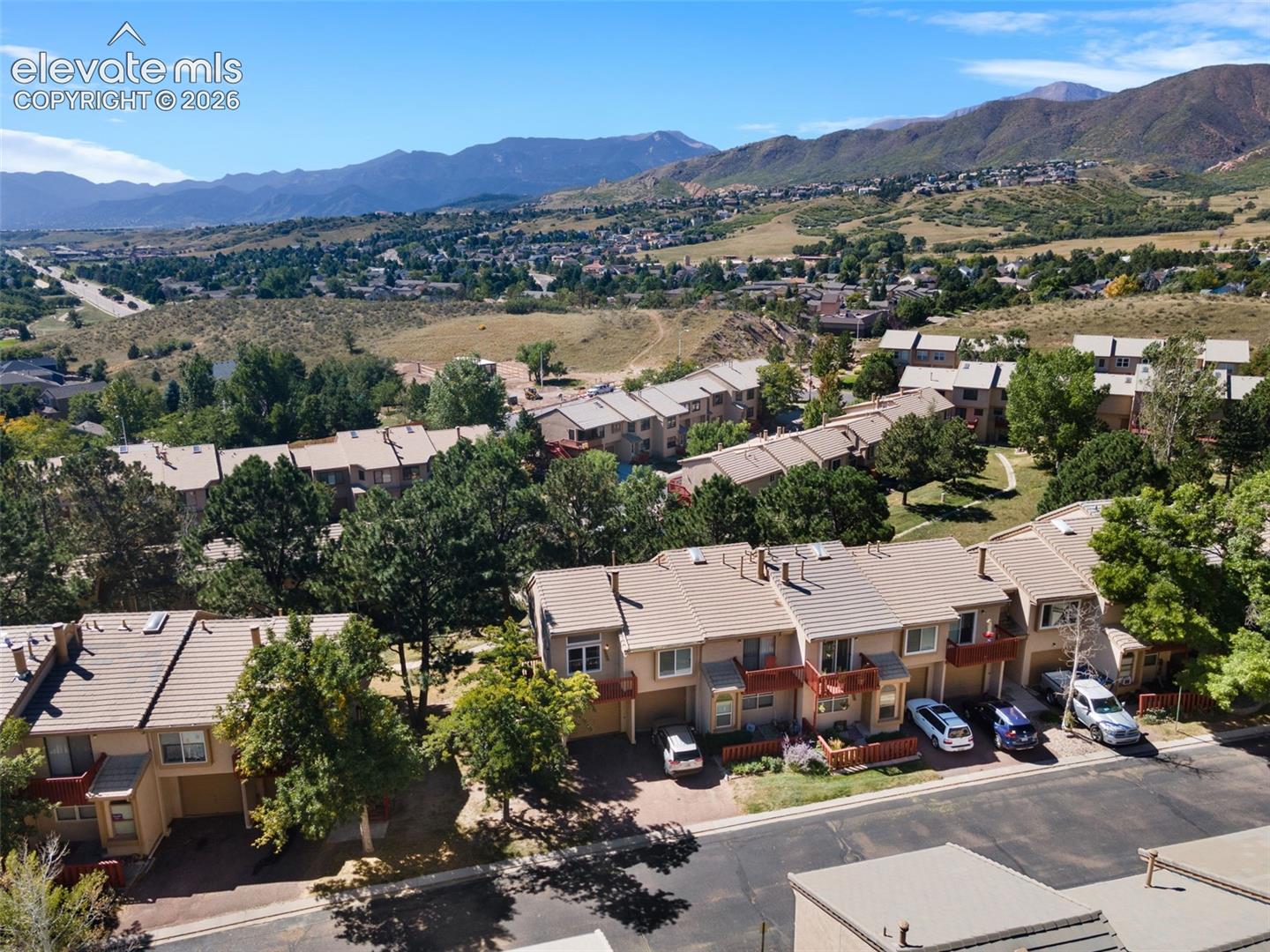 Multi-level townhome community featuring tiled roofs, attached garage structures, and expansive mountain range backdrop