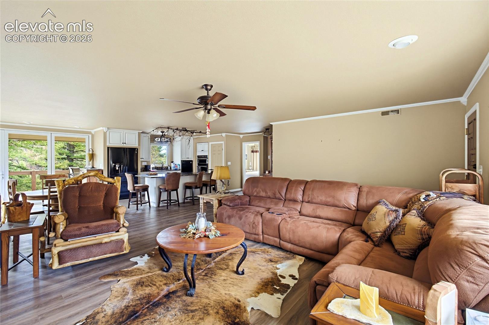 Open-concept interior featuring wood-finish flooring, a kitchen island with bar seating, white cabinetry, and recessed ceiling lighting